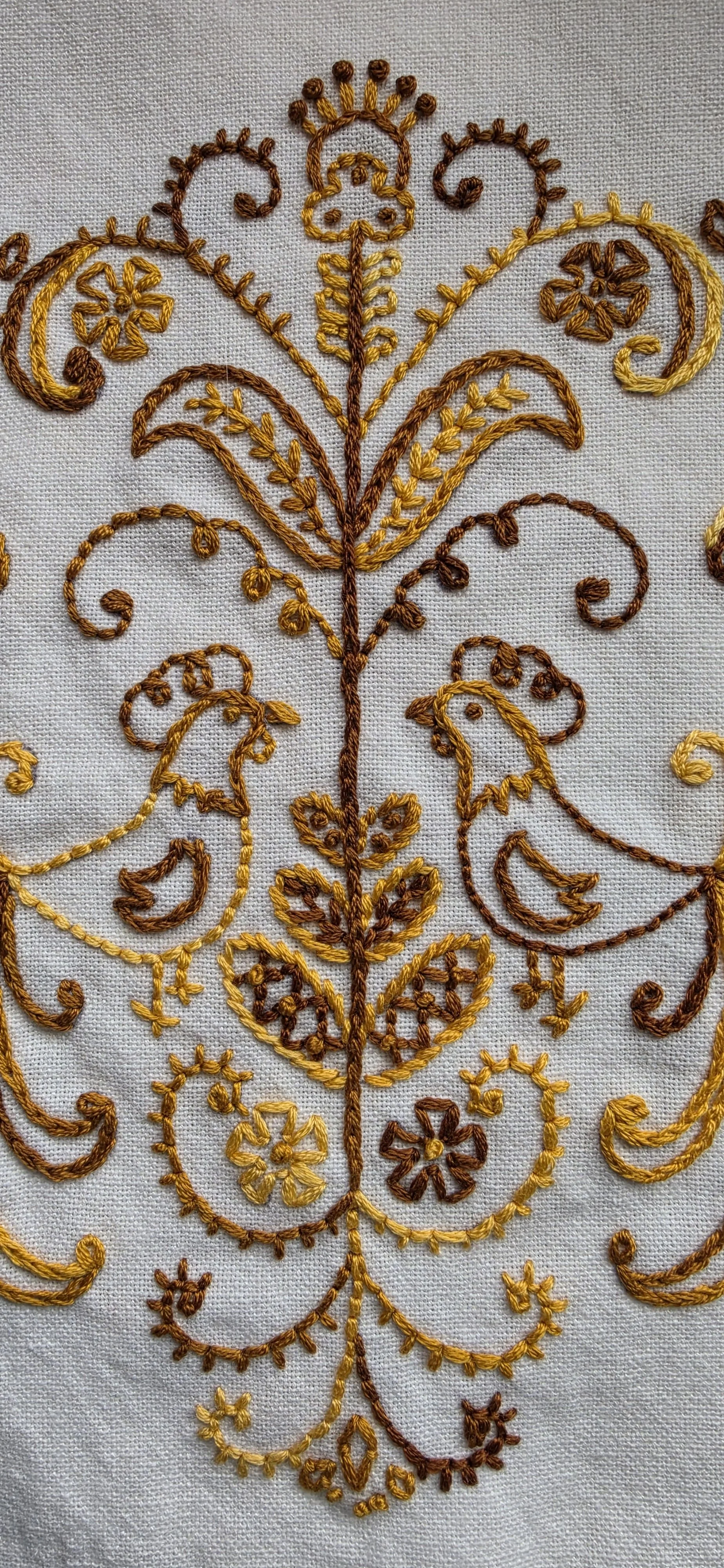 Close-up of detailed hand embroidery in gold, mustard and brown thread on farmhouse kitchen towel