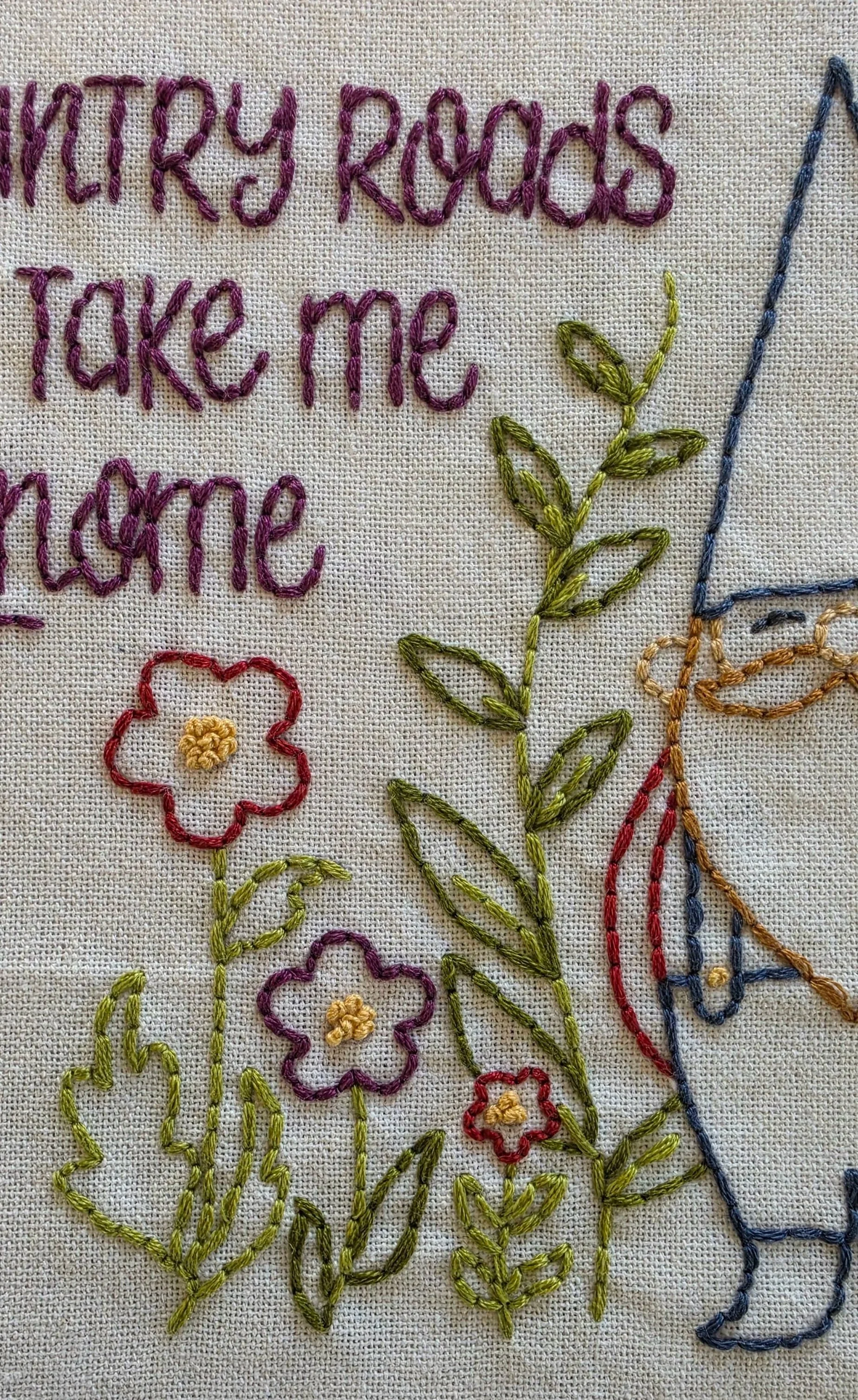 Close-up of the hand-stitched country gnome with a blue hat, tan mustache, and red beard.