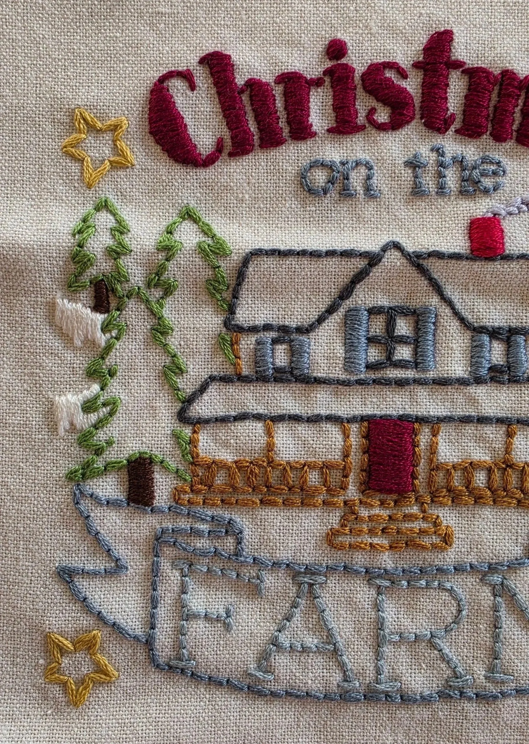 Close-up of the embroidered farmhouse and Christmas lettering on the cotton kitchen towel.