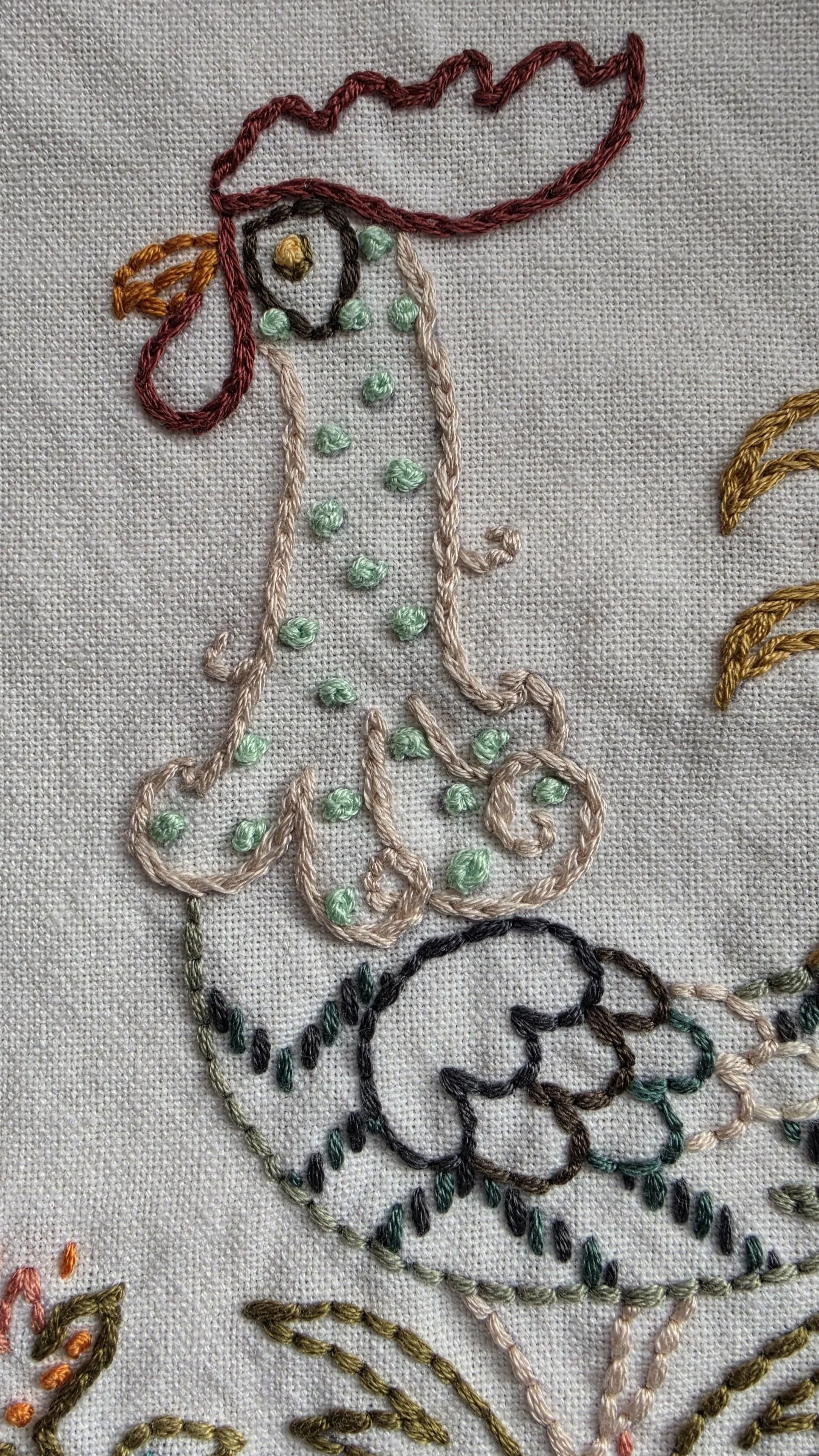 Close-up of hand embroidered rooster with colorful stitched feathers