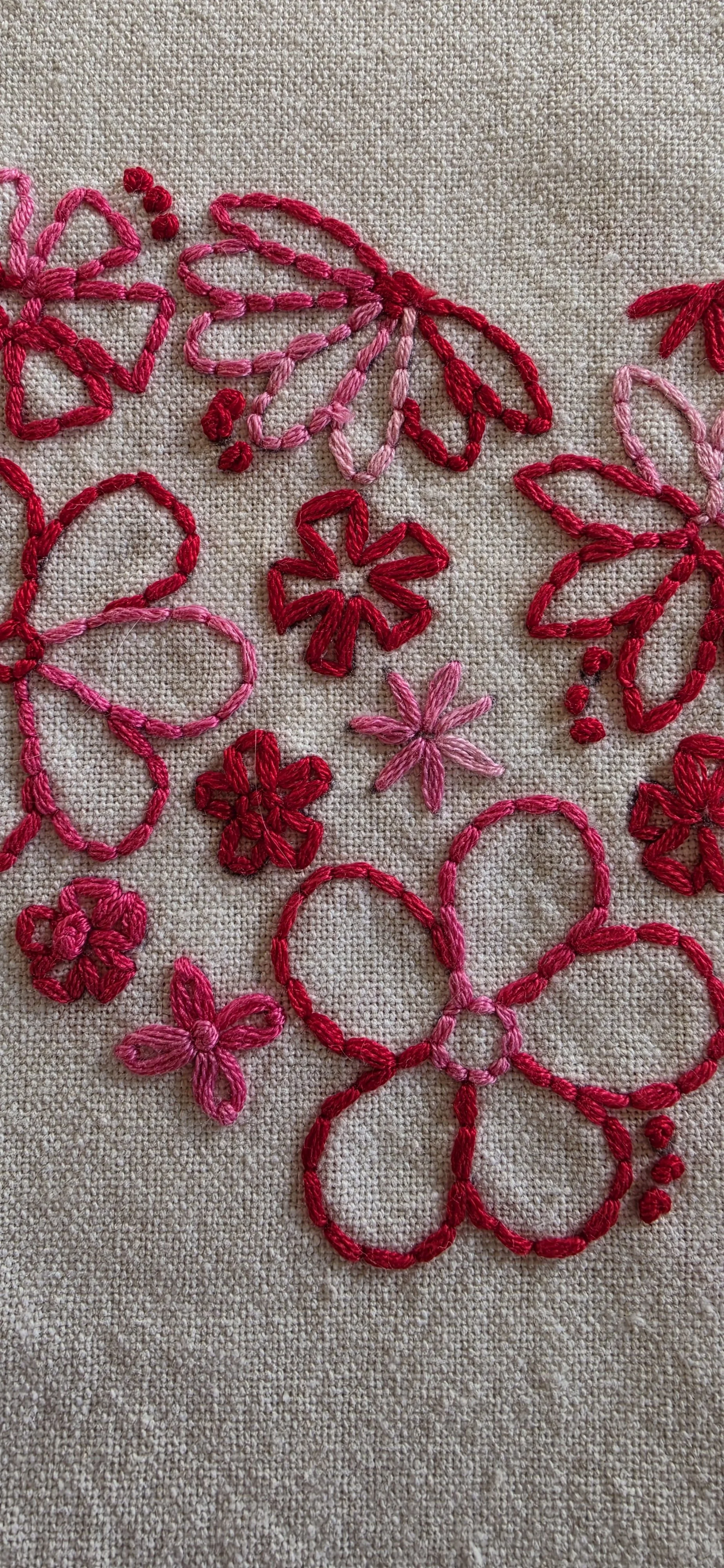 Close-up of the word love embroidered in pink script beneath a heart-shaped arrangement of red and pink flowers.