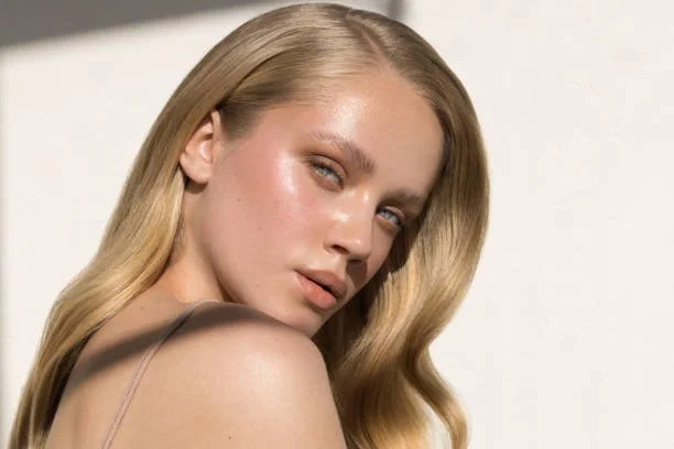 Close-up of a woman with blonde hair and natural makeup looking into the camera.