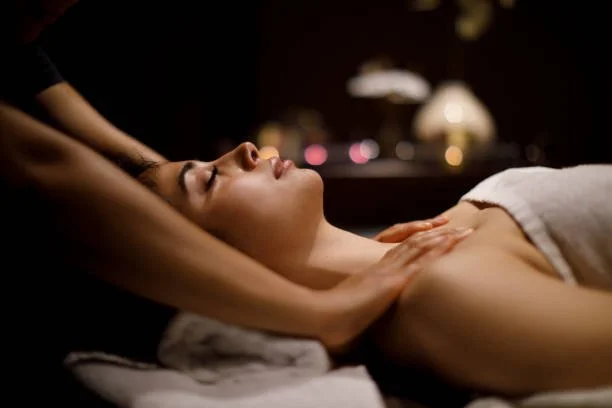Woman receiving a massage while lying down in a dimly lit room.