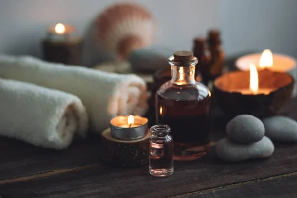 Spa setting with candles, rolled towels, a seashell, and stones.