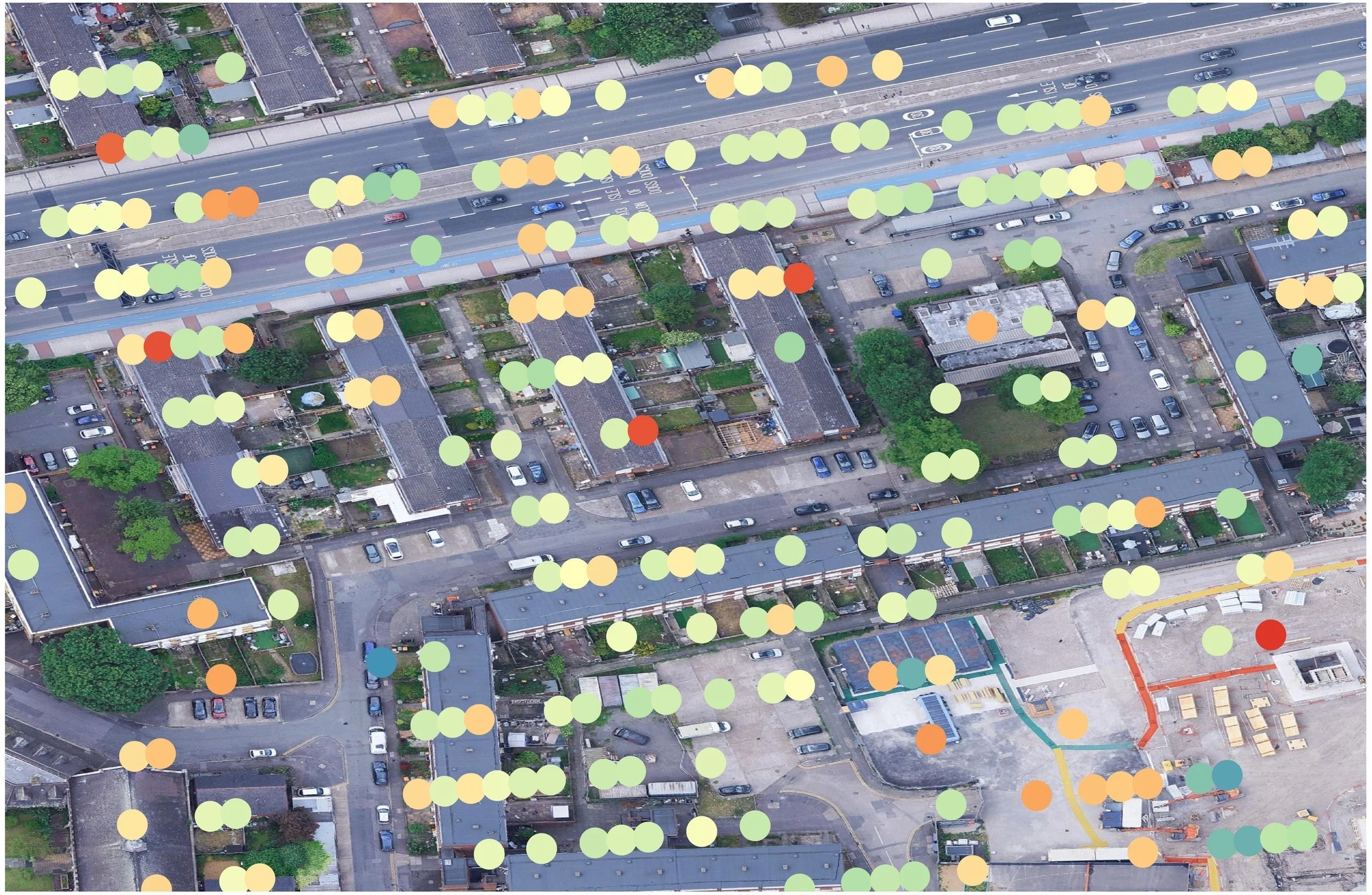 An aerial view of a city neighborhood showing streets, houses, cars, greenery, and a bridge, overlaid with colored dots representing Interferometric Synthetic Aperture Radar (InSAR) Persistent Scatterer (PS) data points.