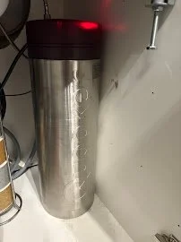 Stainless steel trash can with a red lid in a room corner.