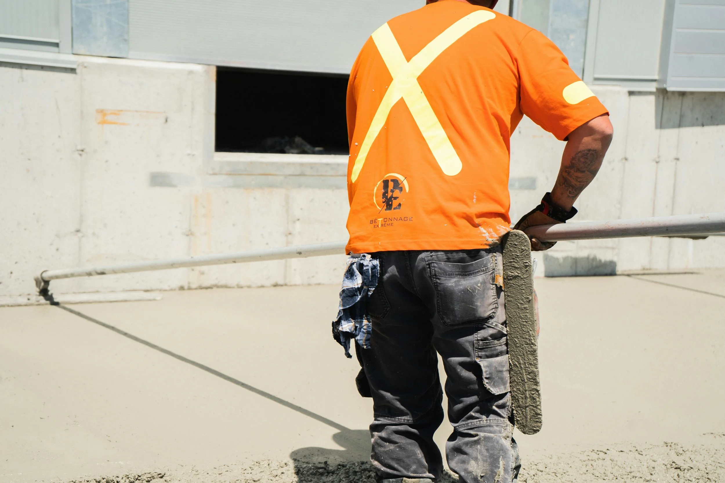 Construction worker smoothing concrete on a building site, representing trade work and commercial insurance coverage