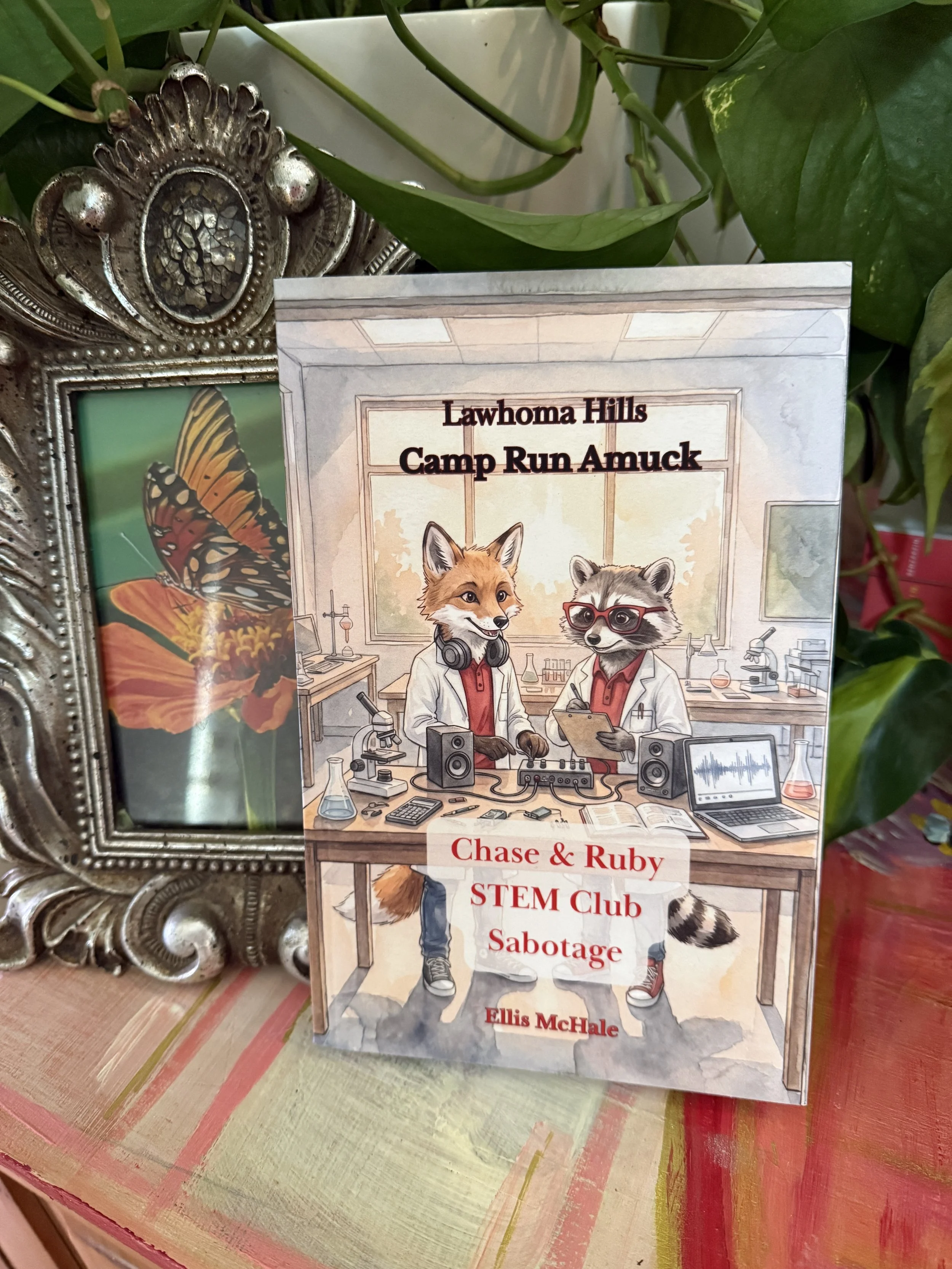Book cover titled 'Lawhoma Hills: Camp Run Amuck' Chase & Ruby STEM Club Sabotage featuring anthropomorphic animals, a fox and a raccoon dressed as stem kids, in a laboratory setting, with the author and Ellis McHale.