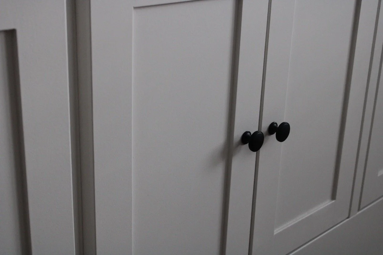 Close-up of a white cabinet with black knobs.