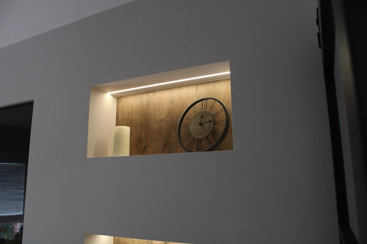 Interior wall with built-in display shelf for storage, containing decorative objects. 