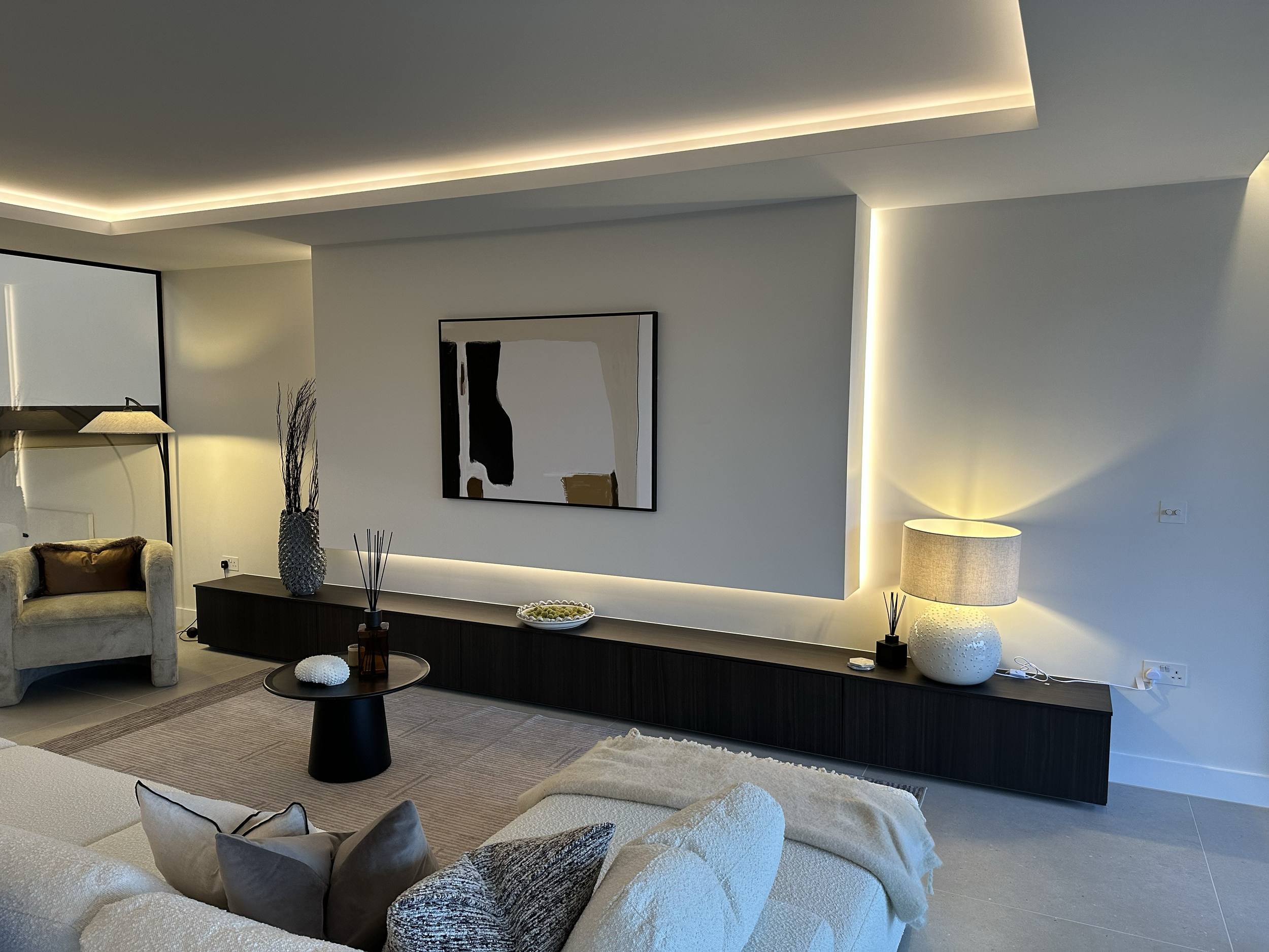 Ultra modern, minimalist TV wall in a living room with a floating wall with integrated lighting, a wall-mounted TV. 