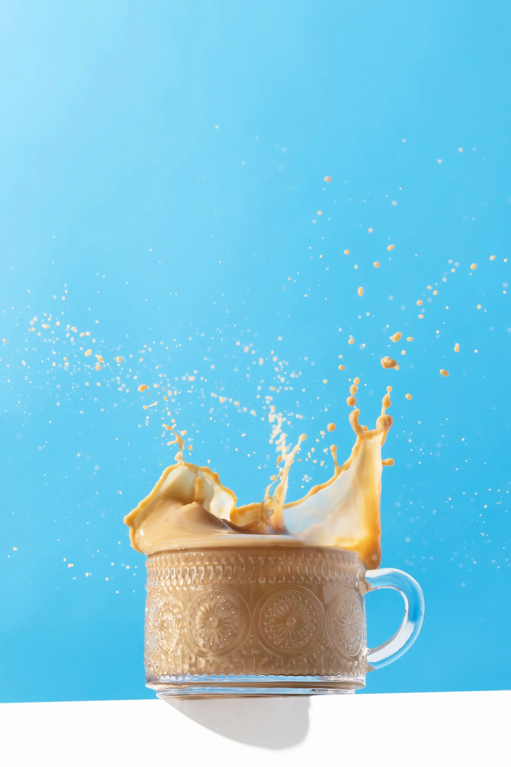 Coffee mug with splashing coffee against a blue background.