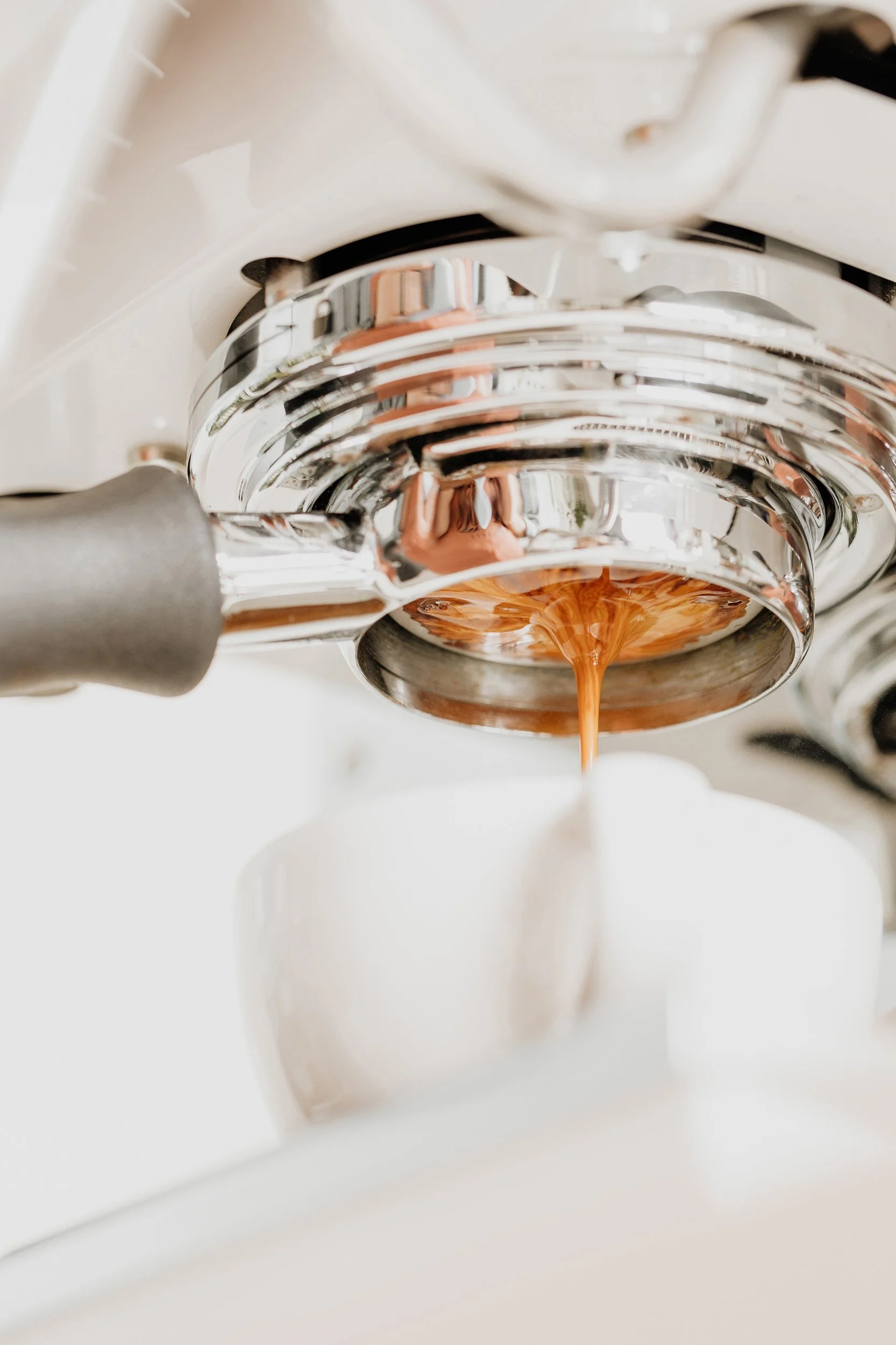 Close-up of espresso machine dispensing coffee into a white cup.