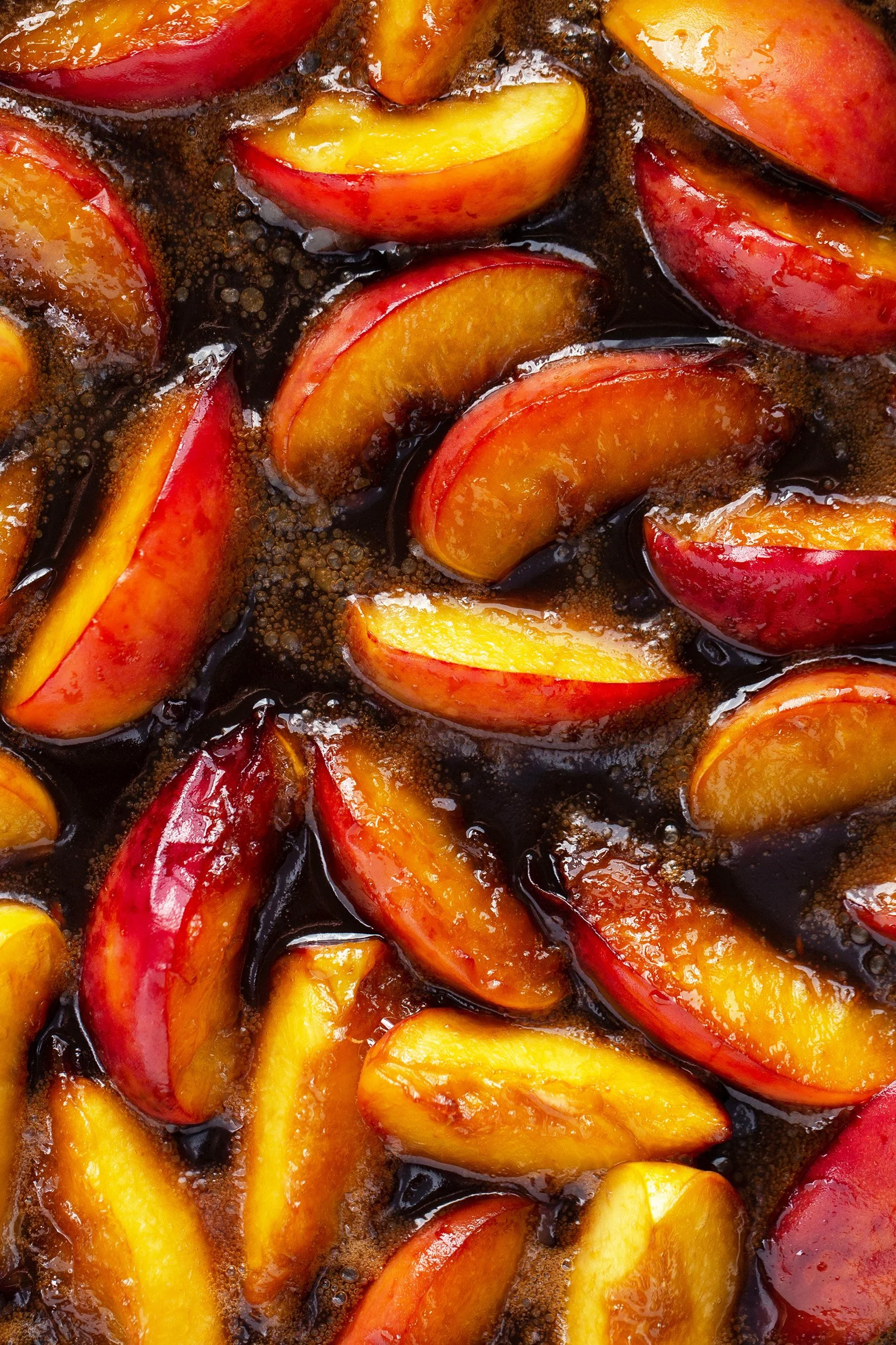 Close-up of sliced peaches in dark syrup.
