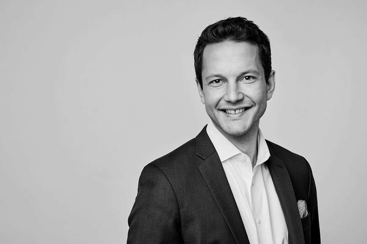 Black and white portrait of a smiling man in a suit and white shirt, facing slightly to the right.