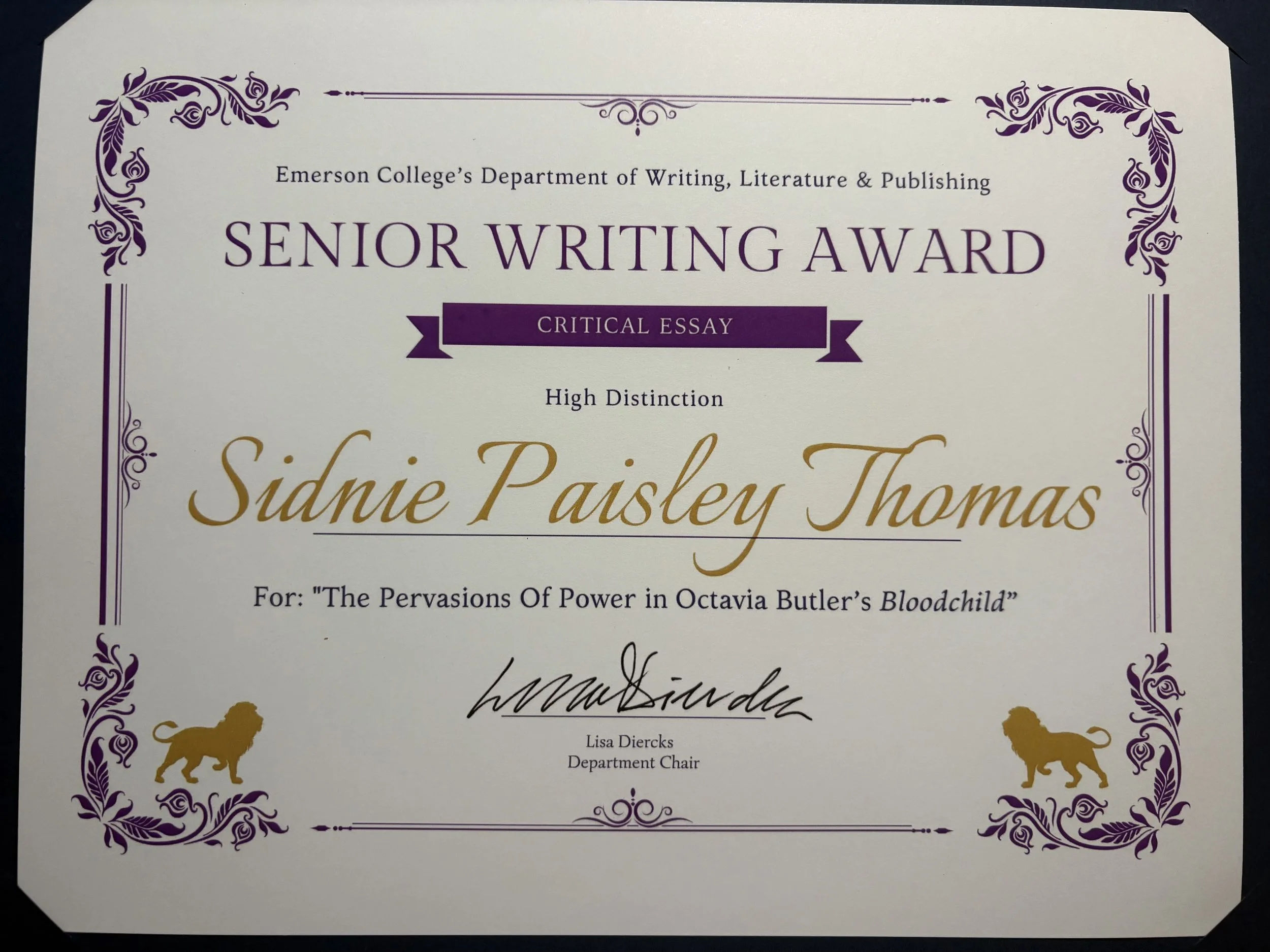 Certificate titled 'Senior Writing Award' with purple floral border, gold lion silhouettes, and black and gold cursive text. It recognizes Sidnie Paisley Thomas for a critical essay, signed by Lisa Diercks, Department Chair.