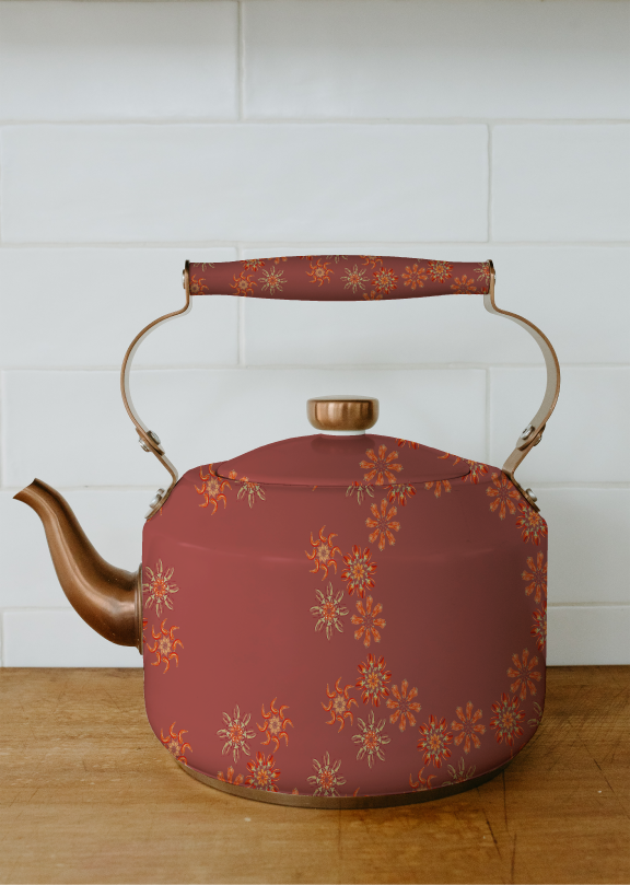 A vintage-style red and gold floral patterned tea kettle on a wooden surface against a white tiled wall.