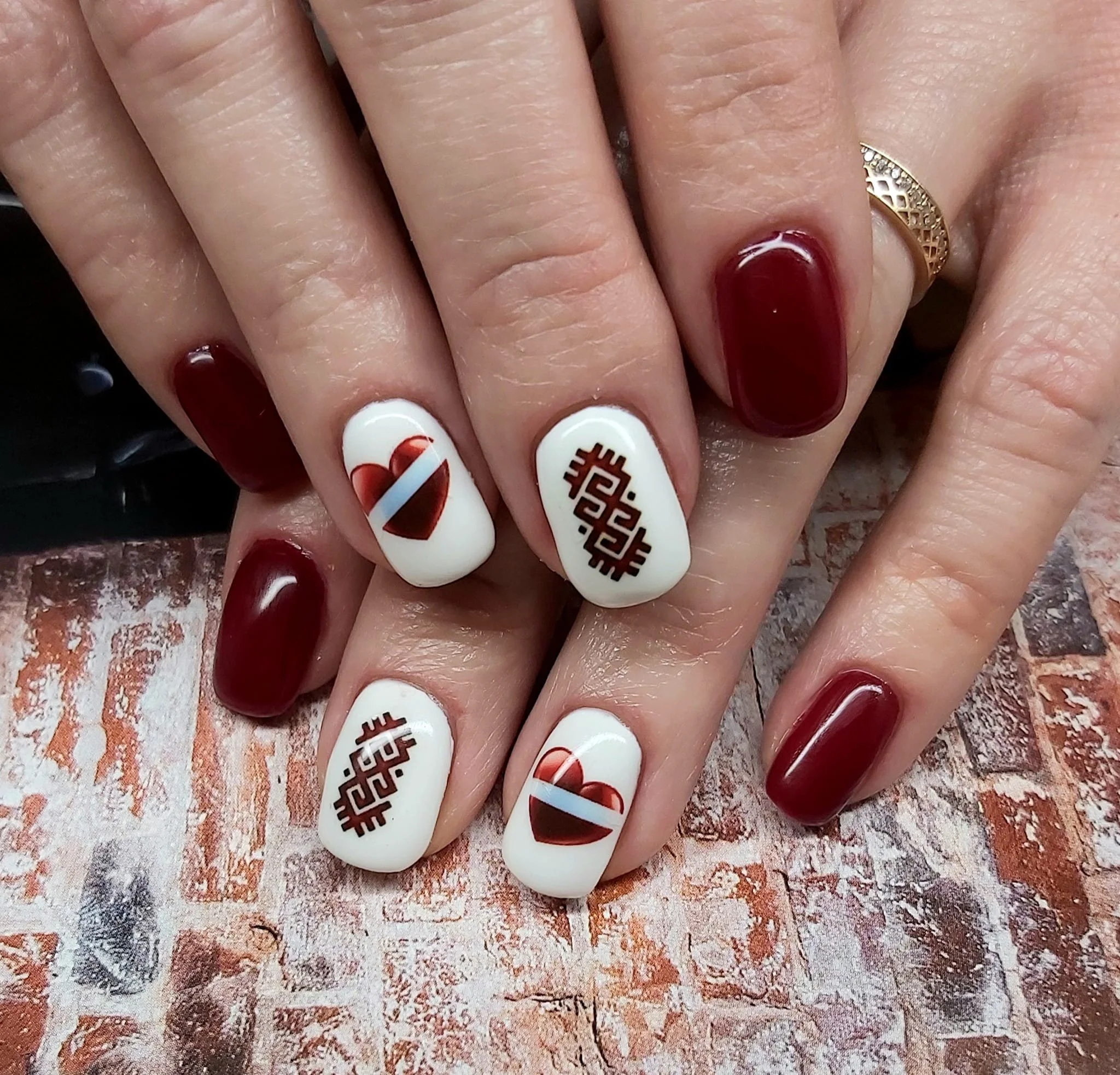 Nagi ar tumši sarkanu laku dažiem nagiem un baltiem nagie latvijas karogu un sirdspukstu līnijas dizainu
