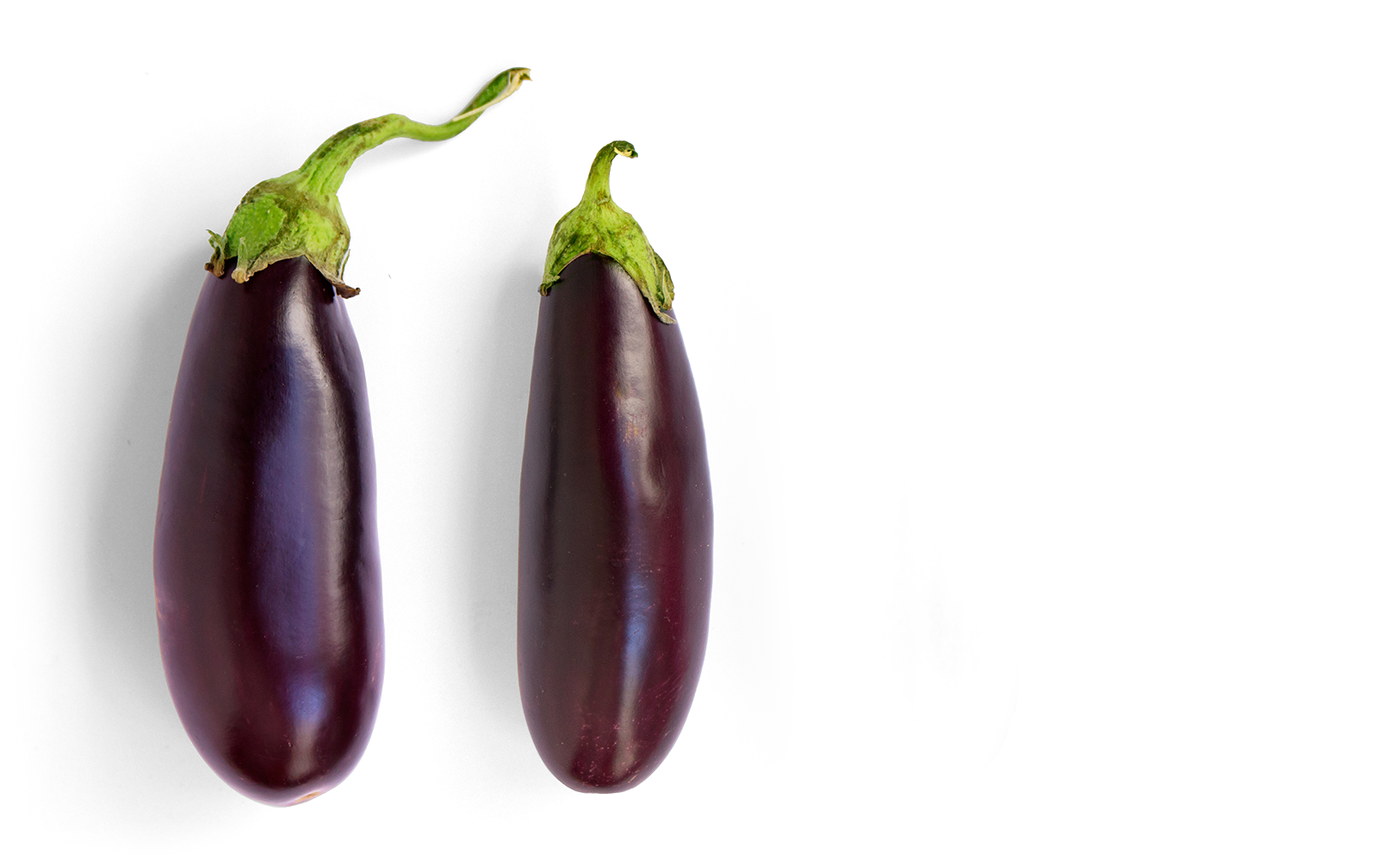 Two eggplants with deep purple skin and green stems against a black background.