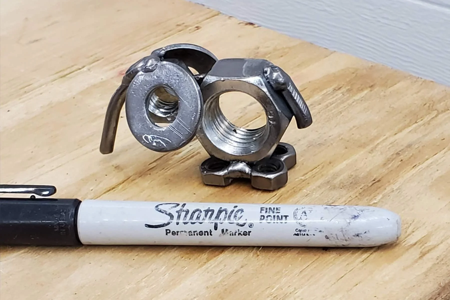 A sculpture of an elephant made from various metal parts, with a sharpie to show size