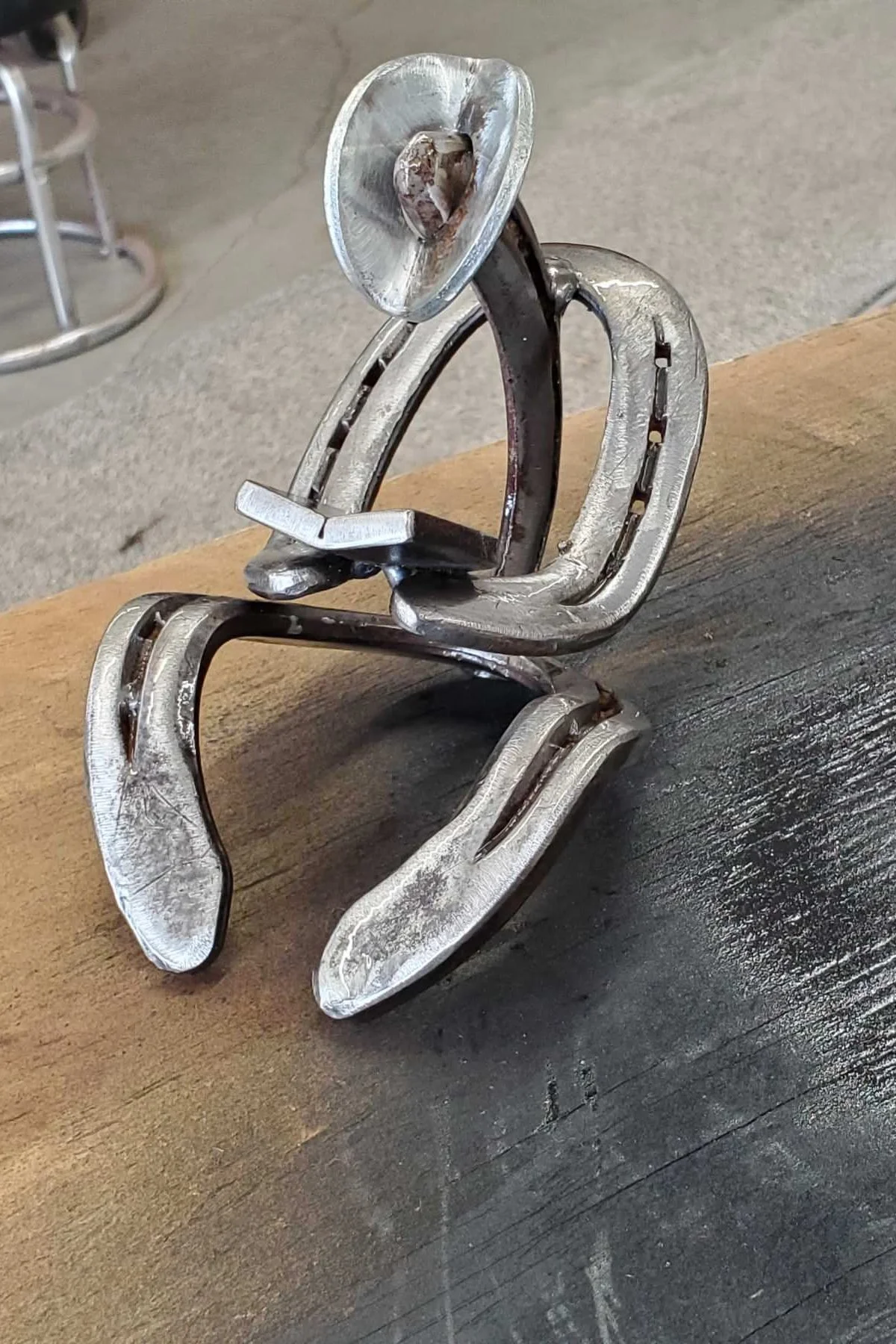 Metal sculpture of a person sitting and reading, placed on a wooden surface.