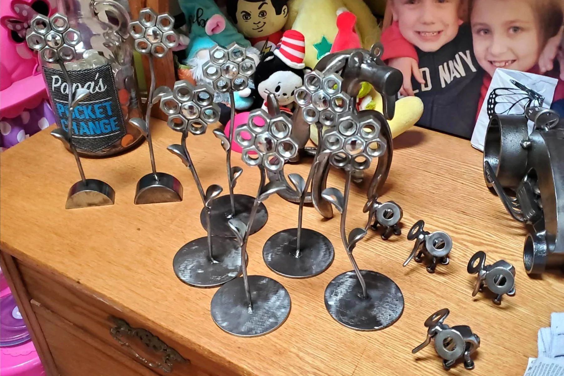 Metal floral sculpture and small metal figurines on a wooden surface, 