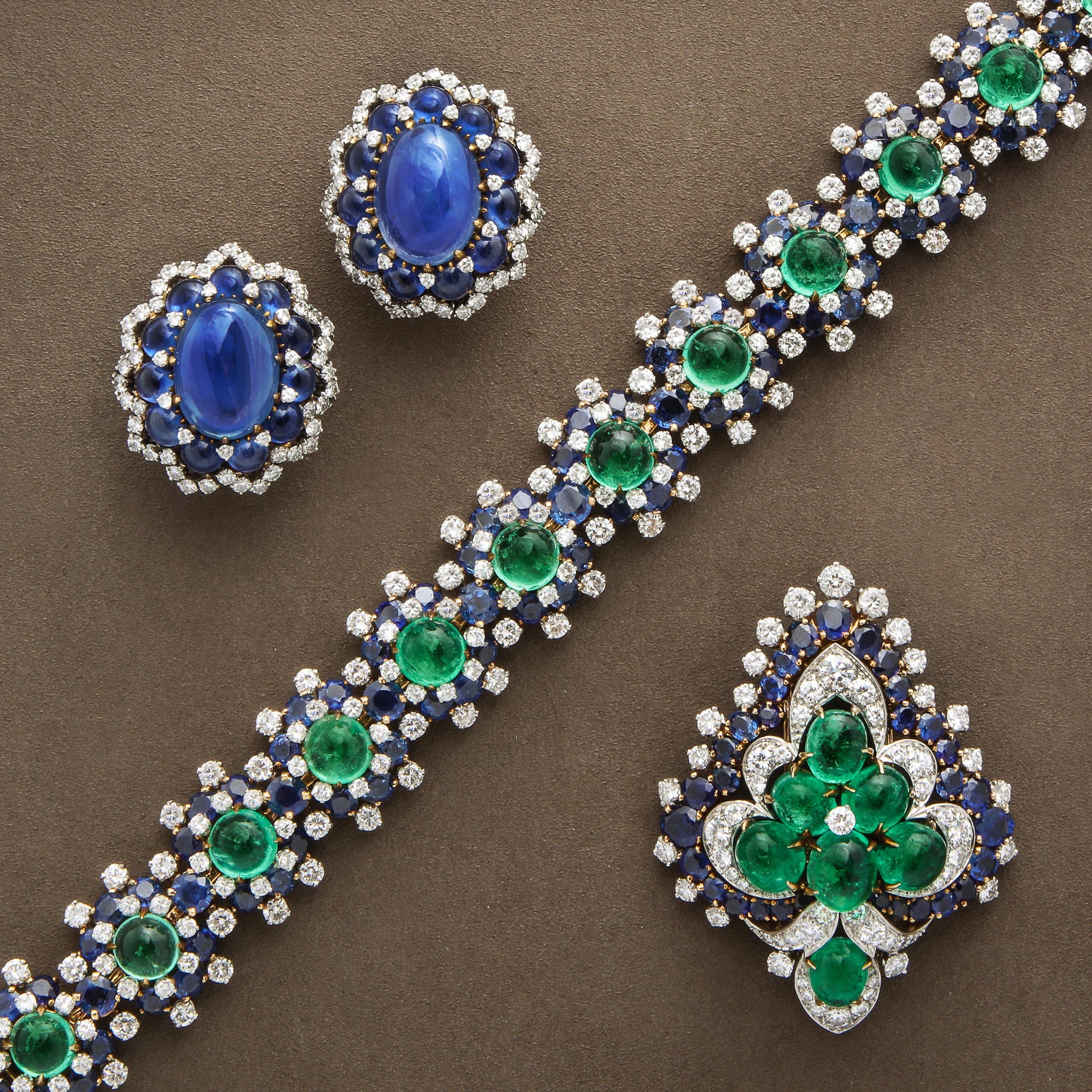 Signed collectible vintage jewelry by Bulgari featuring blue sapphire, colombian emeralds, including earrings, a bracelet, and a brooch.