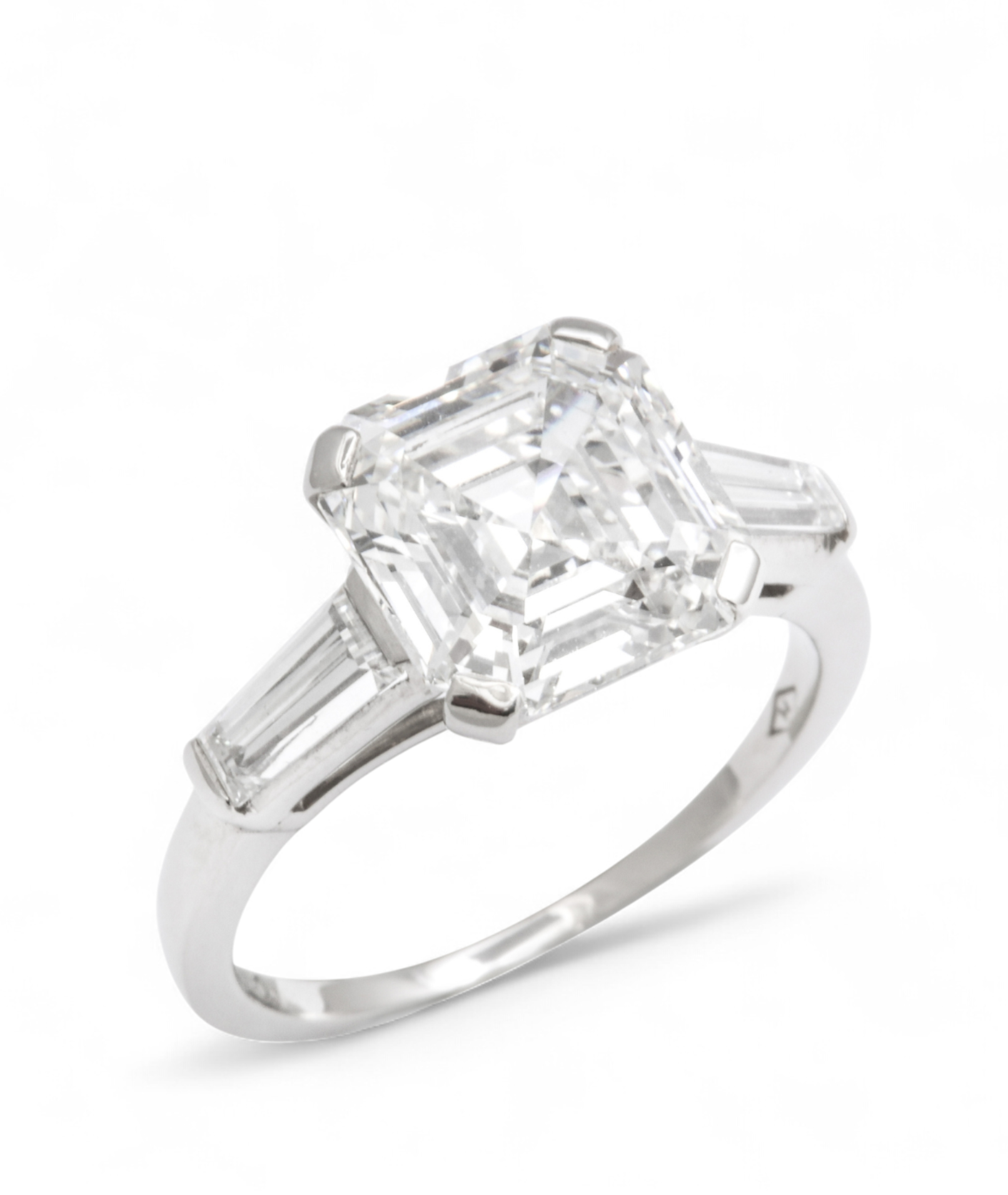 Custom Donna Vock engagement ring. A silver ring with a large, square-cut clear gemstone in the center, flanked by baguette-cut gemstones on each side.