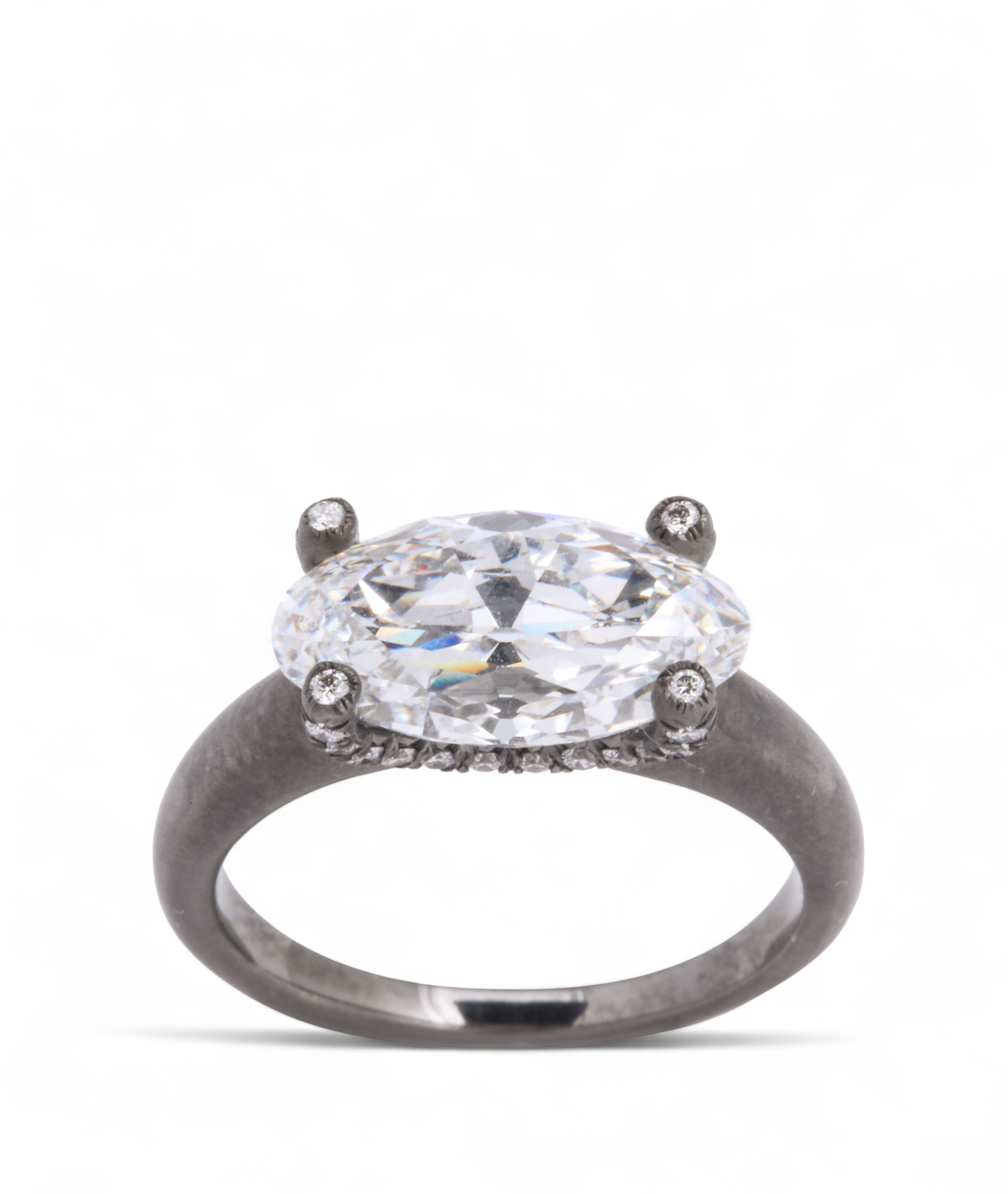 Custom Donna Vock engagement ring. Close-up of a diamond engagement ring with a large oval-cut diamond set in a four-prong setting on a silver band with small diamonds along the sides.