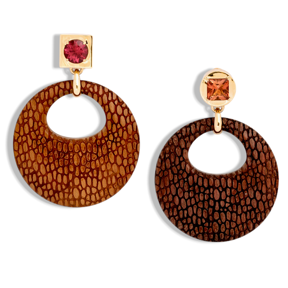 Custom Donna Vock. Pair of circular earrings with textured brown natural wood, each attached to a gold square with a colored gemstone, one red and one orange.