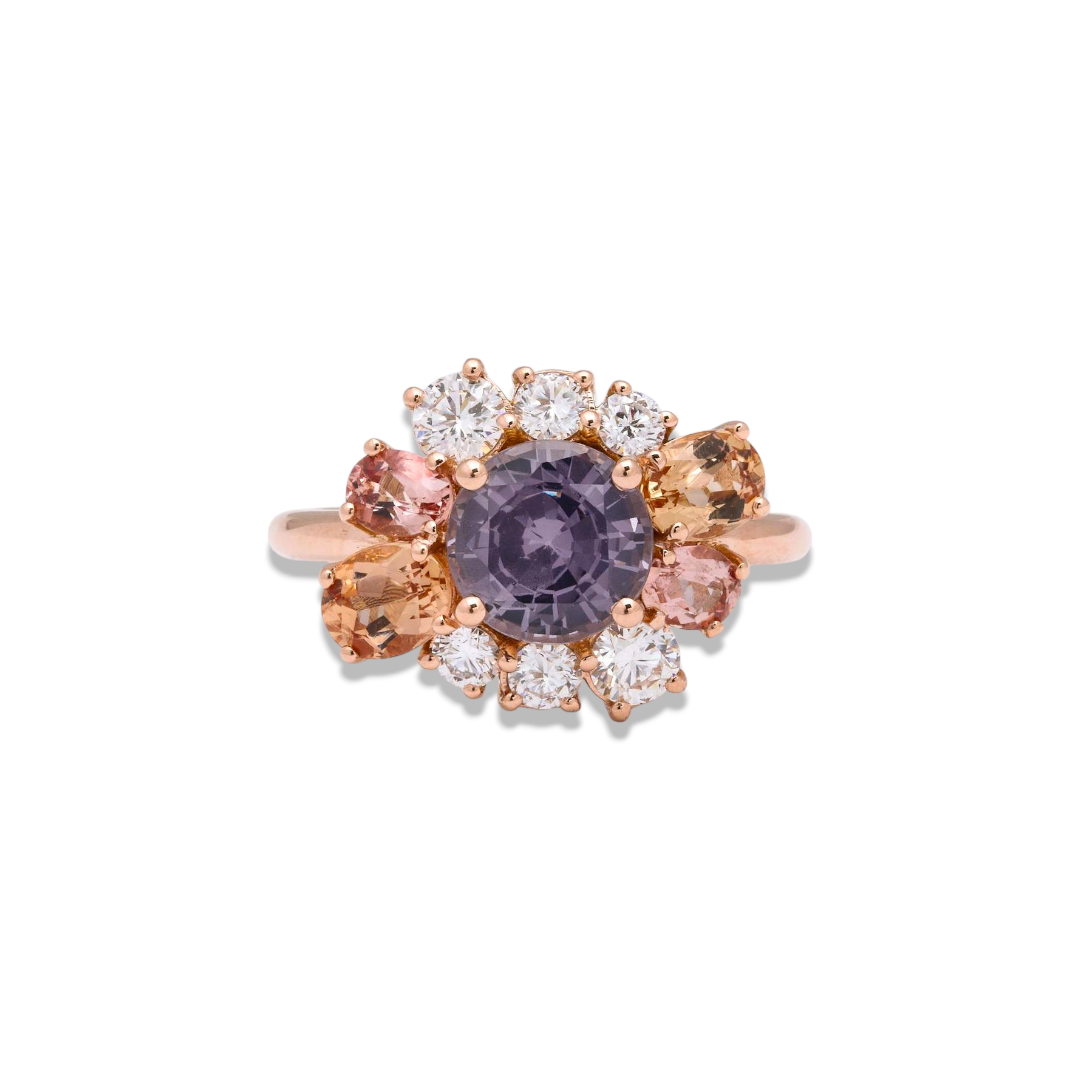Custom Donna Vock. A ring with a purple central gemstone, surrounded by smaller clear, pink, and peach-colored gemstones, set in a rose gold band.