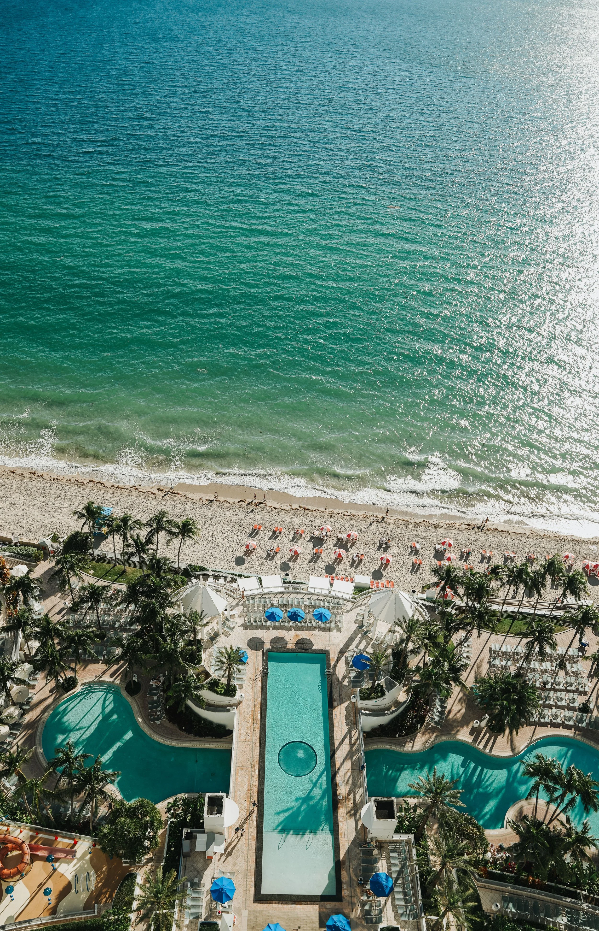 Aerial view of a beachfront resort with swimming pools and palm trees