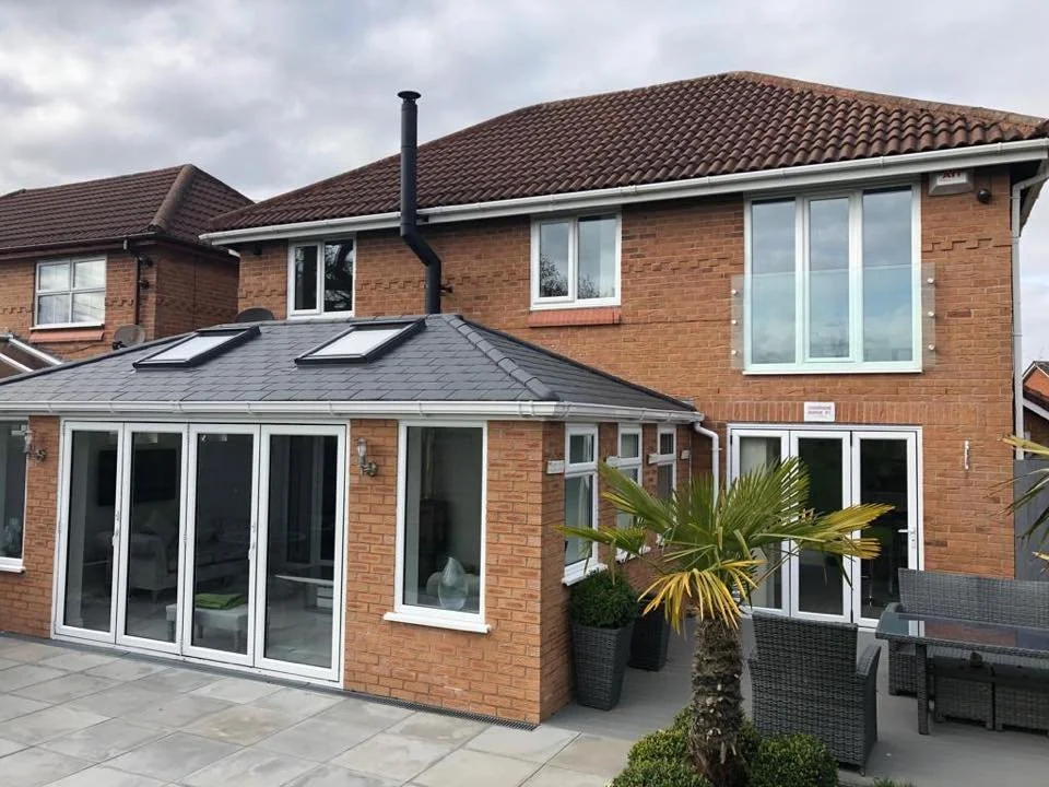 Extension with warm roof, bifold doors and picture windows,  small patio area with outdoor furniture and a palm tree.
