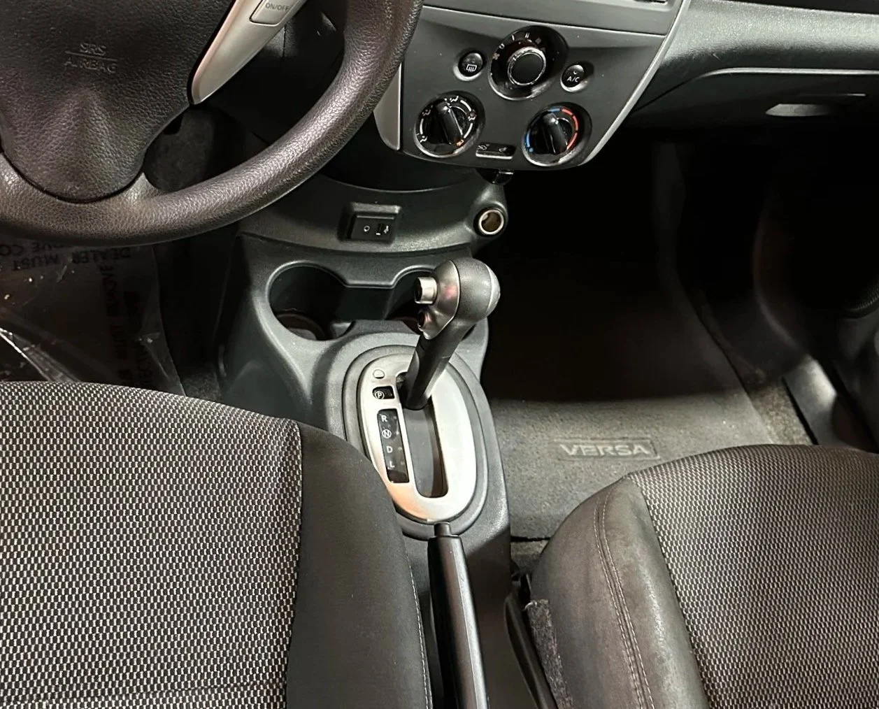 Interior of a car showing the steering wheel, gear shift, climate controls, and front seats.
