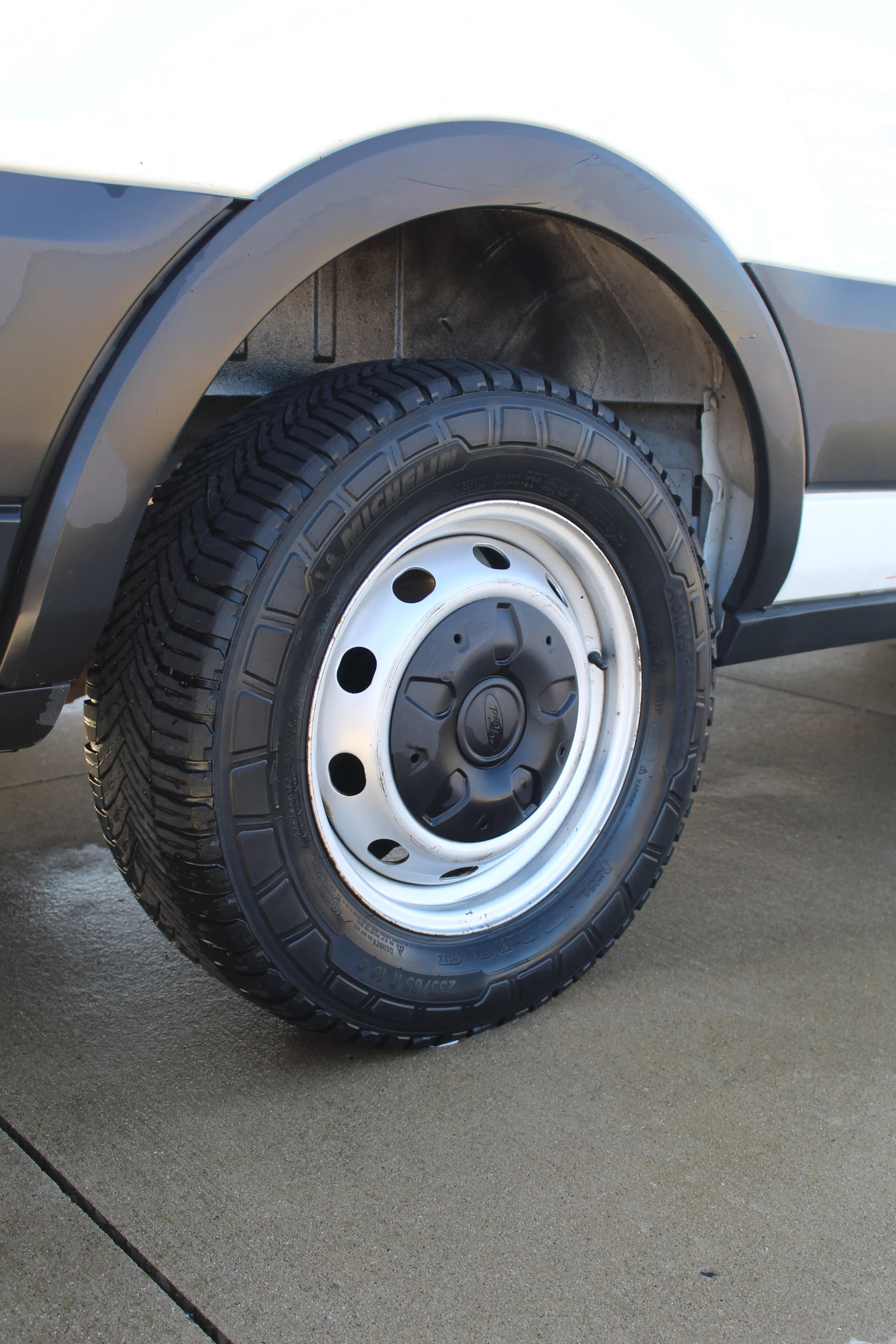 Close-up of a vehicle's front tire and wheel, with the hubcap showing the Ford logo.
