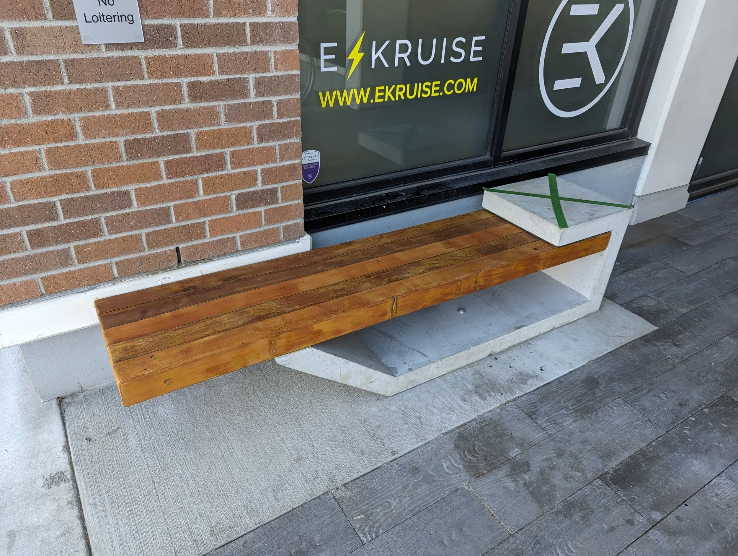 Concrete and wood bench outside a building with a brick wall