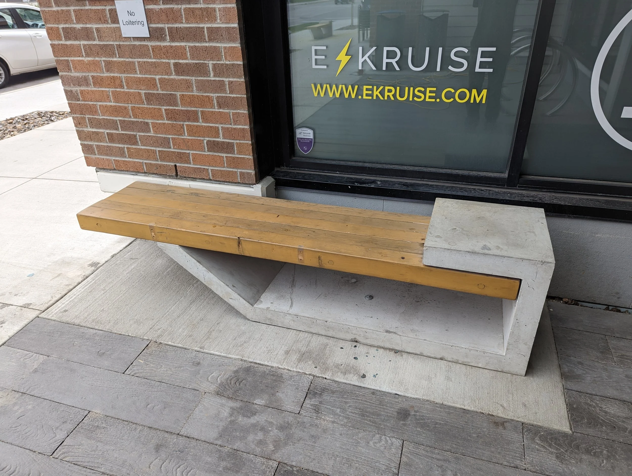 Concrete and wood bench outside a building with a brick wall