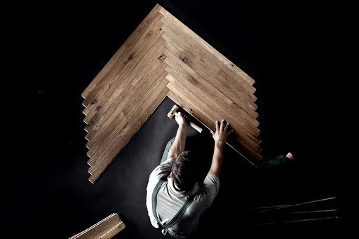 Un hombre instala una tabla de madera en el techo desde una escalera