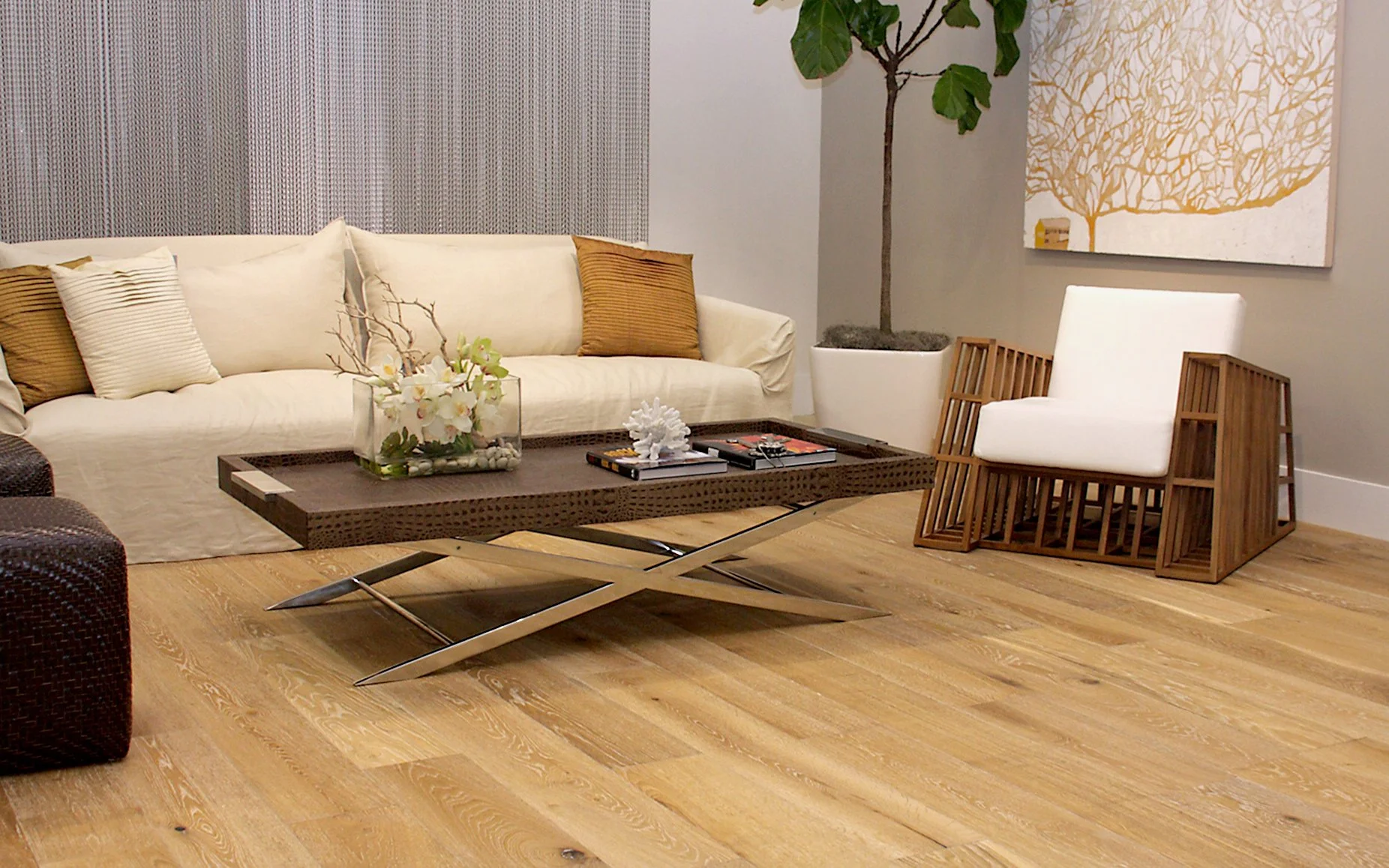 Sala moderna con sillón blanco, sofá beige, mesa de centro de madera y una planta en maceta grande.