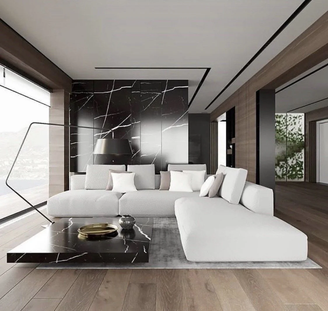 Sala moderna con sofá blanco, mesa de centro de mármol negro con vetas blancas, lámpara de pie y pared de mármol negro con vetas blancas, ventanas grandes con cortinas y plantas en el fondo.