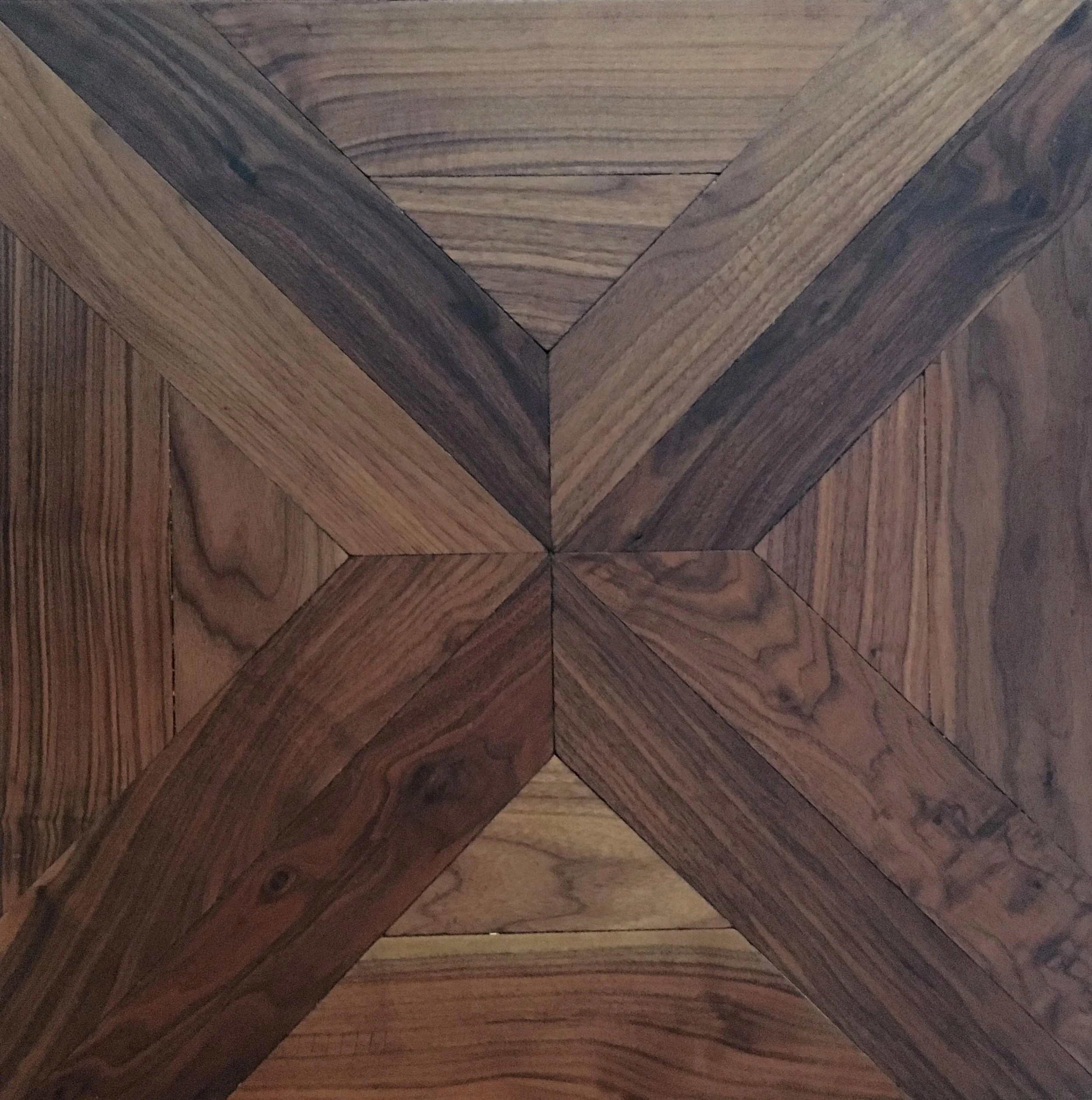 Plano de madera con un patrón geométrico formado por segmentos rectos que se cruzan en el centro, creando un diseño en forma de X.