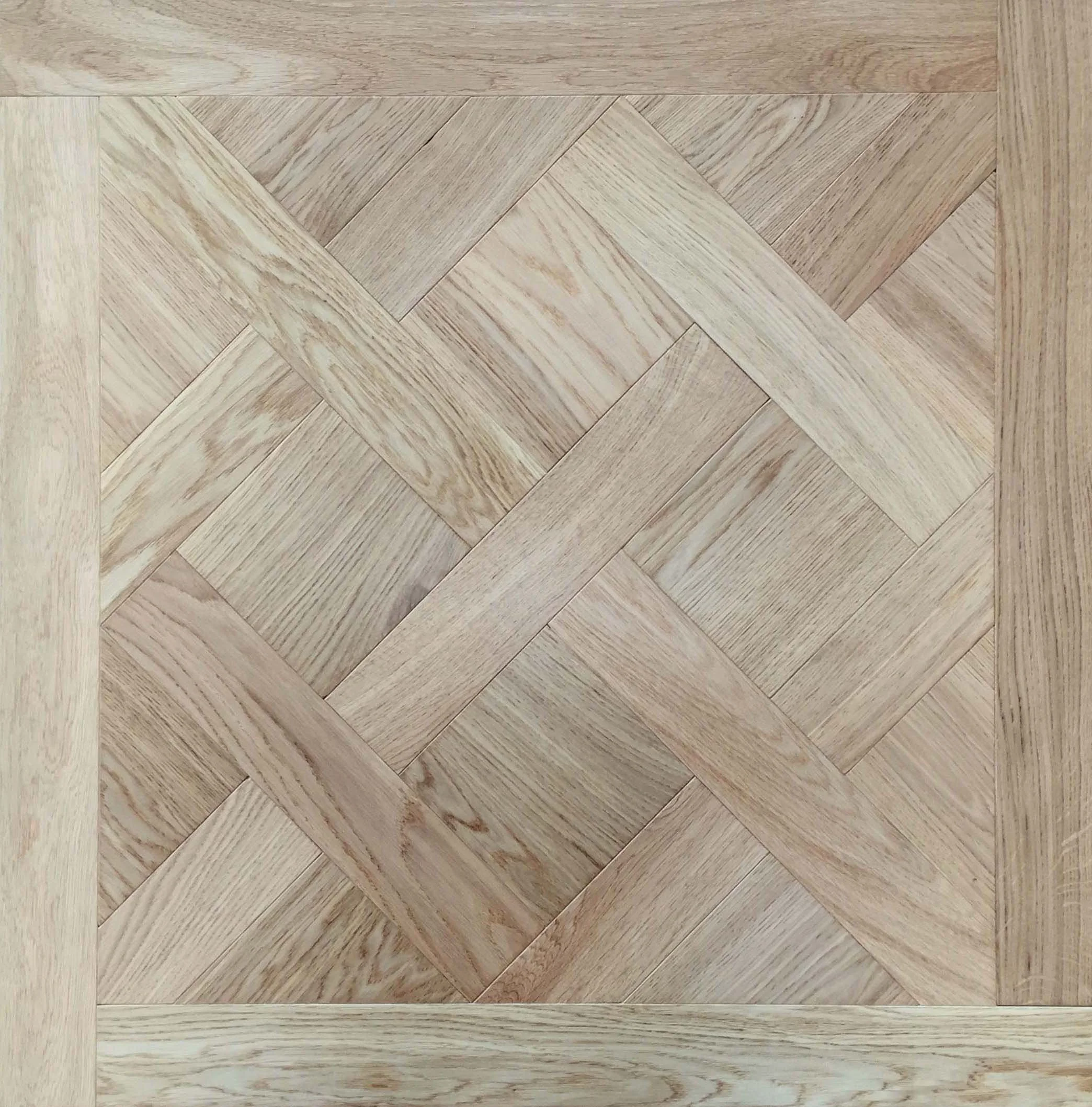 Suelo de madera con patrón en espiga y borde enmarcado.