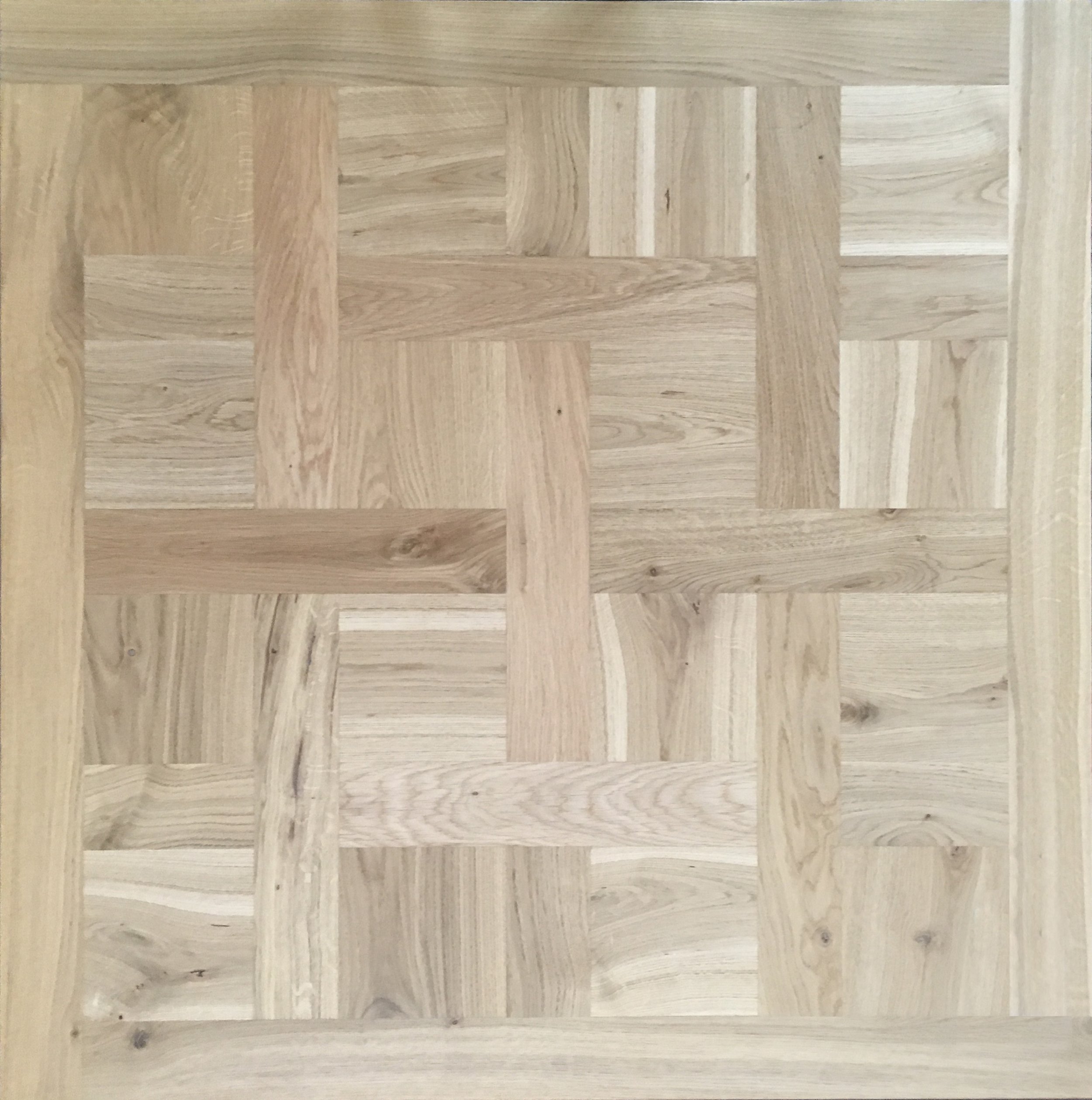 Patrón de parquet de madera con diferentes tonos y vetas formando un diseño en espiga.