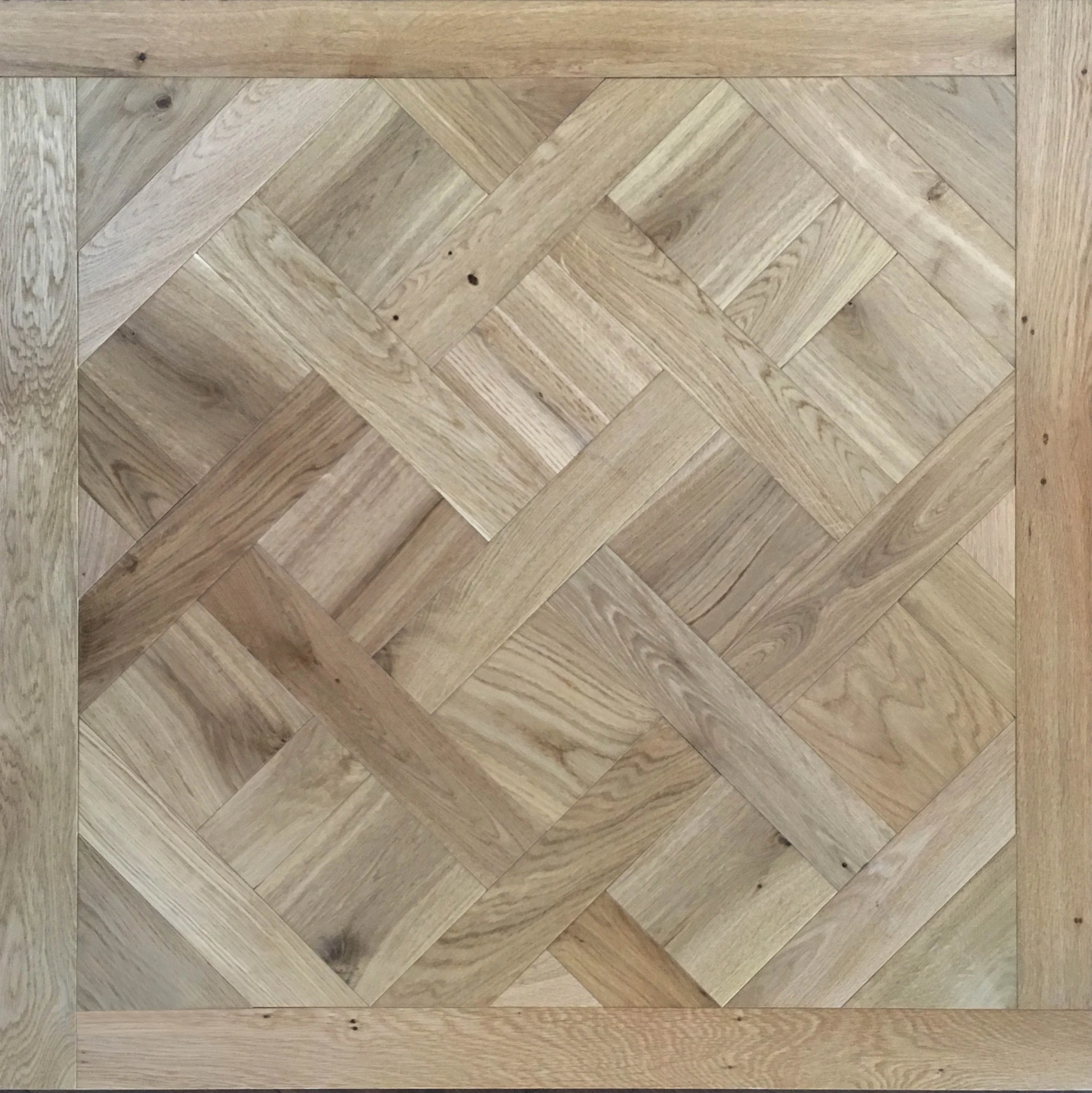 Imagen de un suelo de madera con patrón de parquet en tonos claros, enmarcado por una moldura de madera de tono similar.