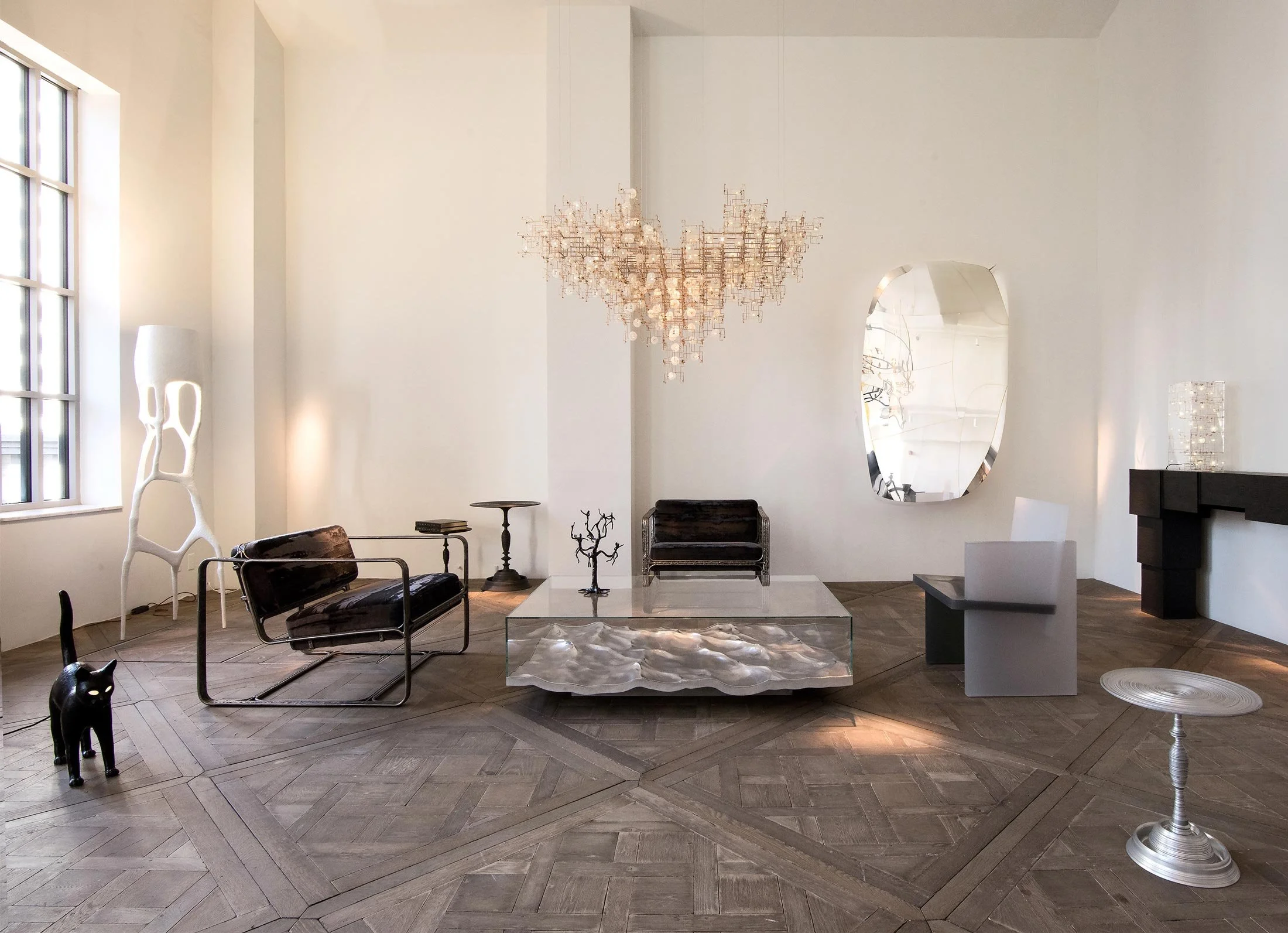 Sala de estar moderna con muebles negros y decoración artística, including una lámpara escultórica blanca, un espejo irregular y una lámpara de techo chandelier