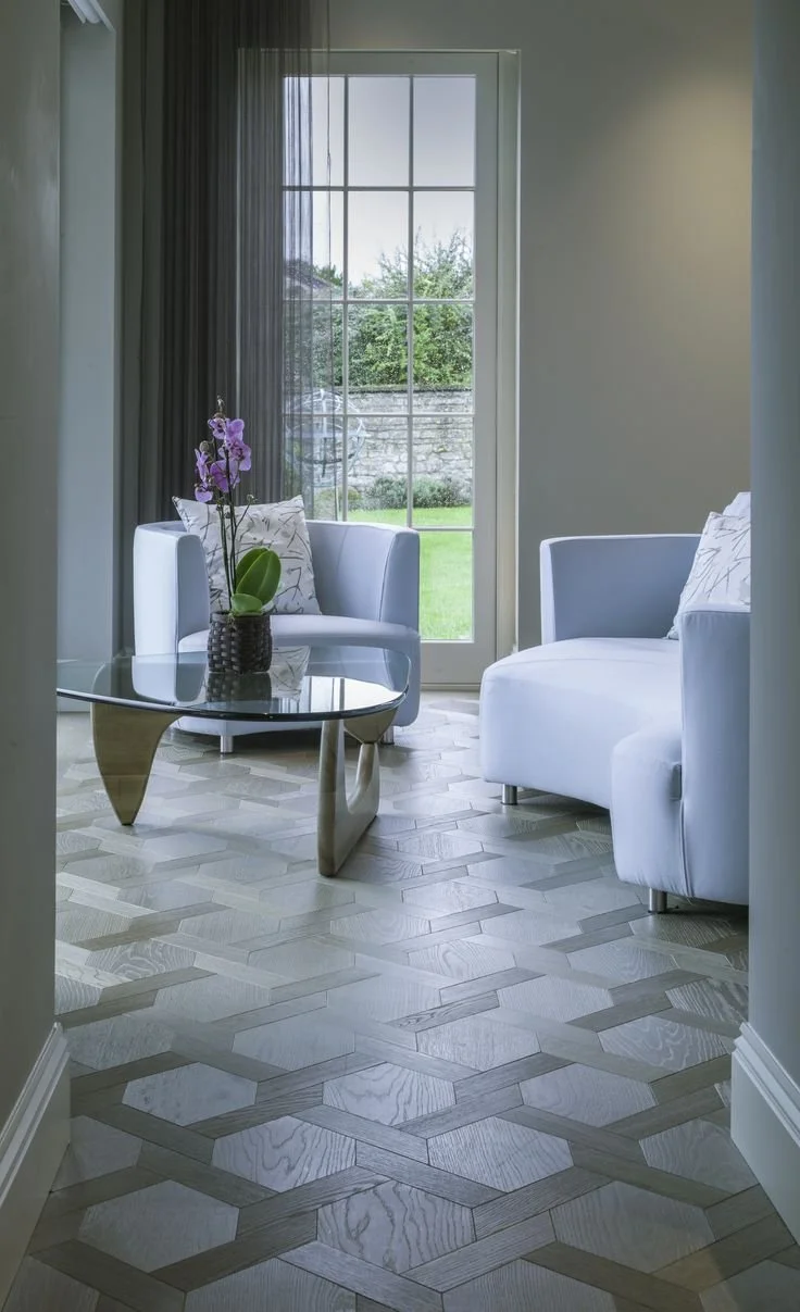 Sala con sillones blancos, mesa de cristal y una planta de flores en una ventana grande con vista al jardín.