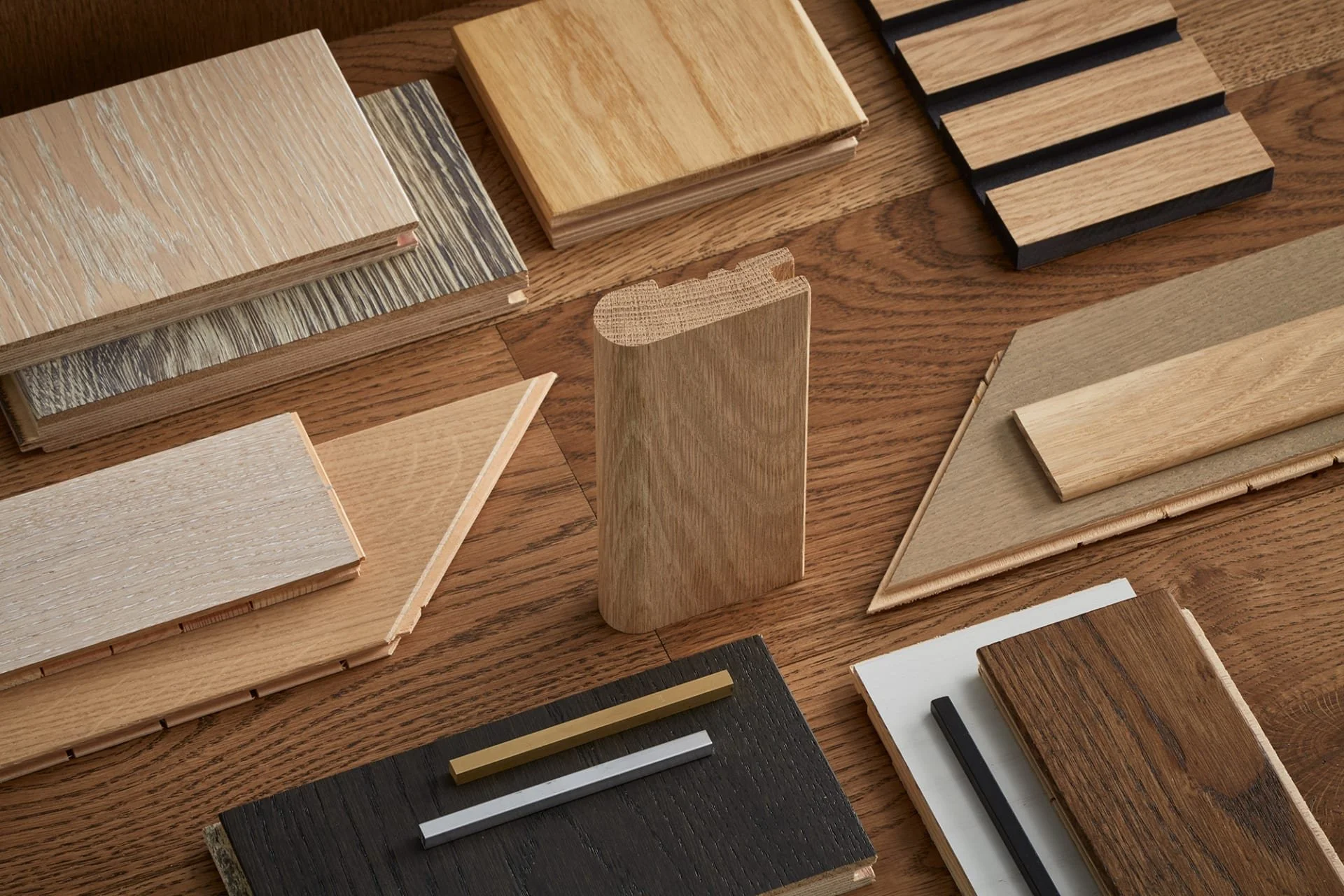 muestras de diferentes tipos de madera y laminados en tonos naturales y oscuros, dispuestos en una mesa de madera