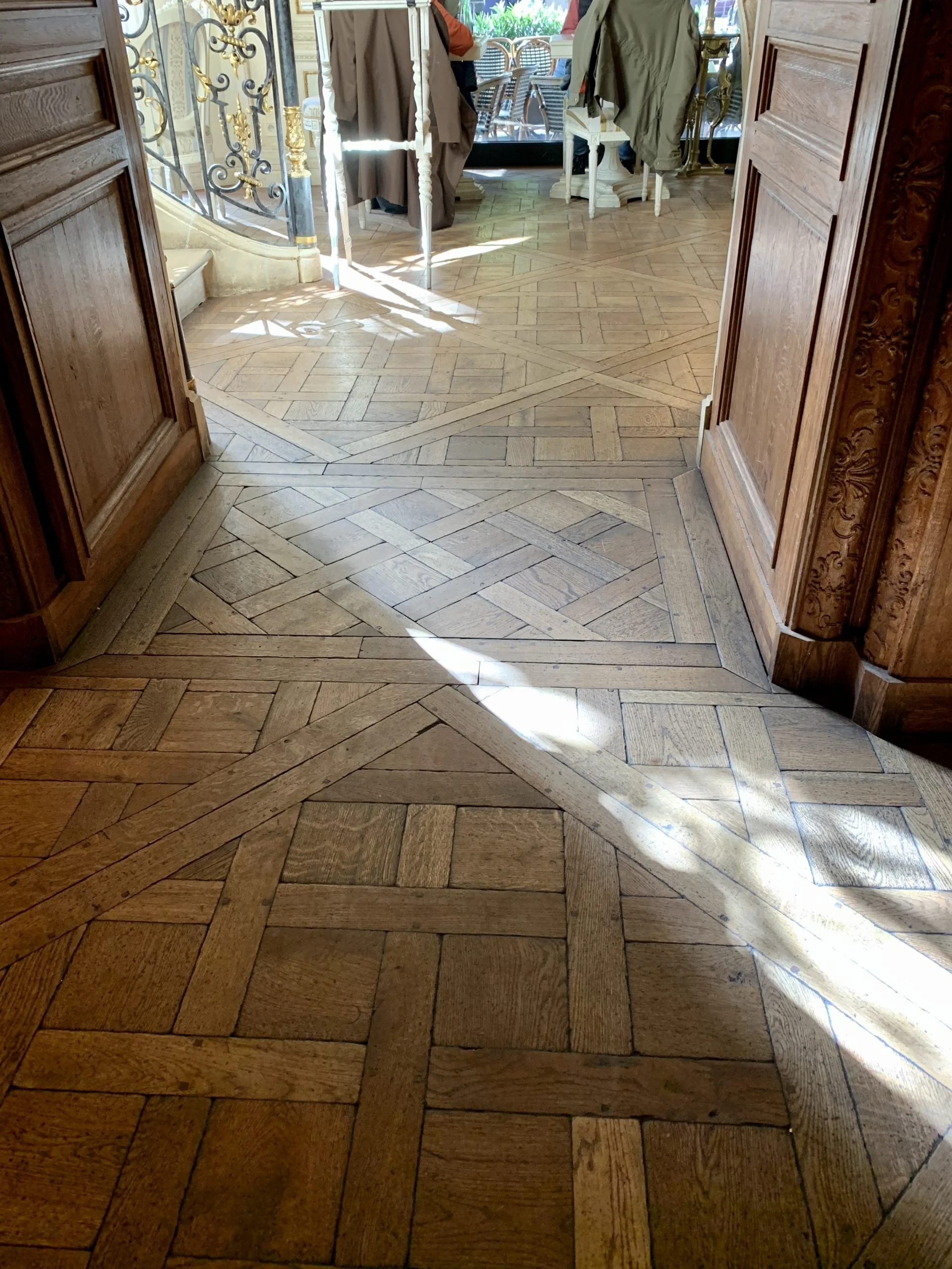 Vista de entrada a un espacio con piso de parquet de madera y una puerta de madera enmarcada.