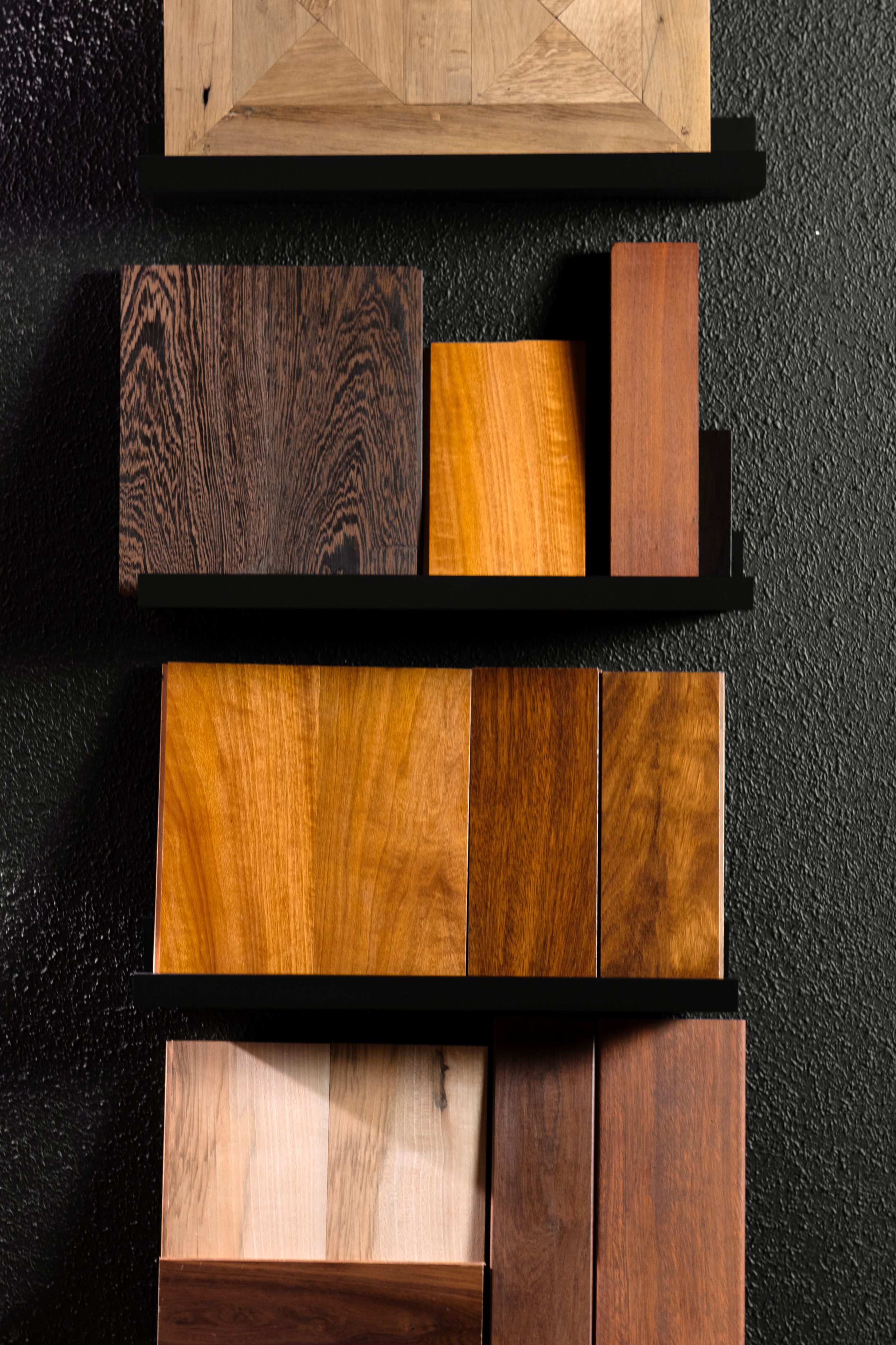 Muestras de diferentes tipos de madera en una pared de fondo negra