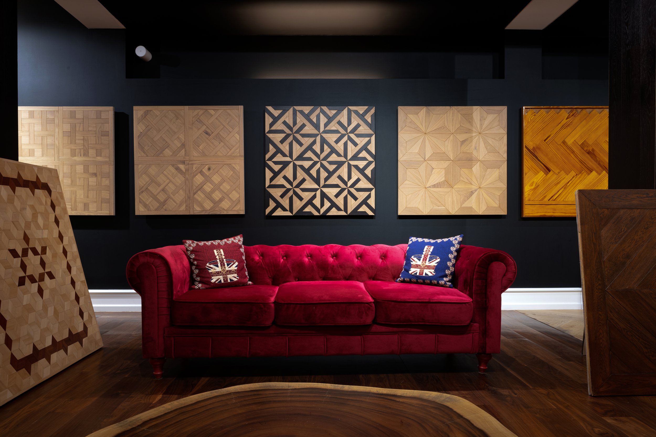 Sala con sillón rojo y cuadros decorativos de madera en la pared, con cojines con la bandera del Reino Unido. 